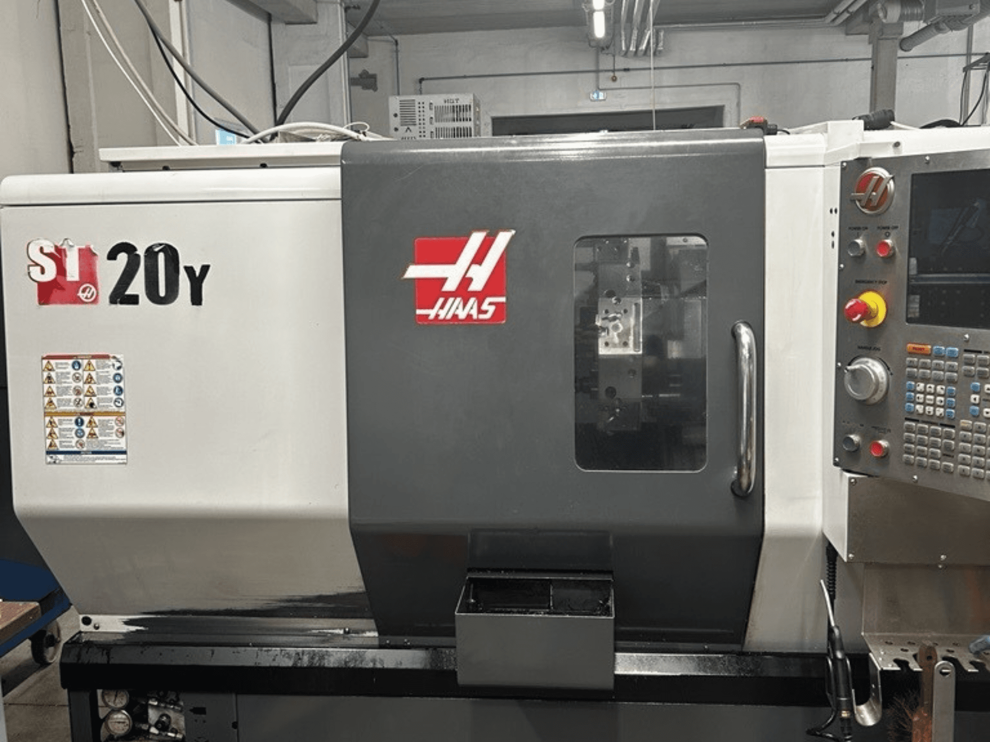 Tour CNC Haas ST-20Y, vue de face, montrant le panneau de commande, les étiquettes de sécurité et la fenêtre opérationnelle.