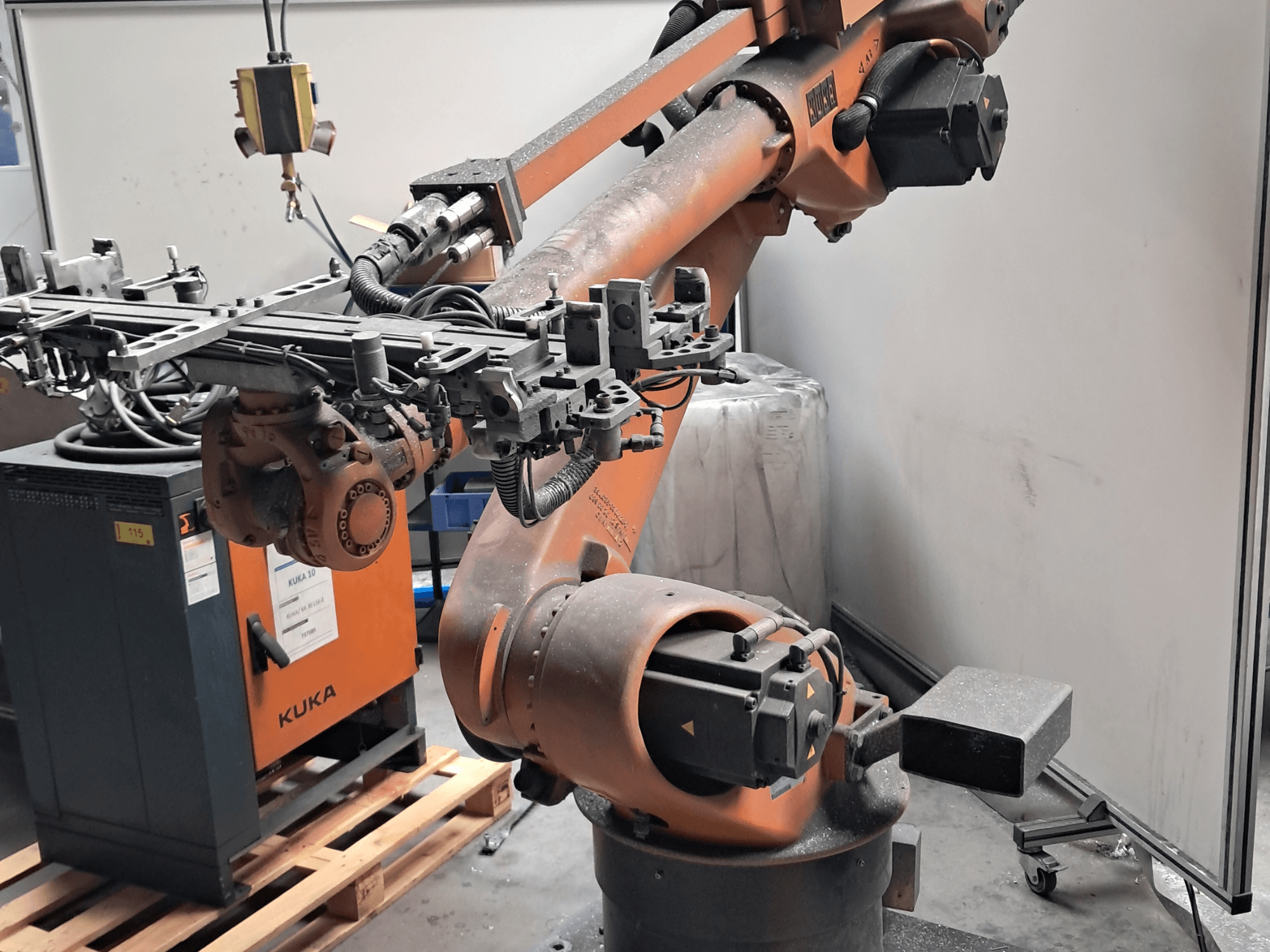 Bras robotisé KUKA KR 30L16-2 vu de profil, doté d'un effecteur terminal sophistiqué et de câbles de commande, placé à côté d'un boîtier de commande KUKA.