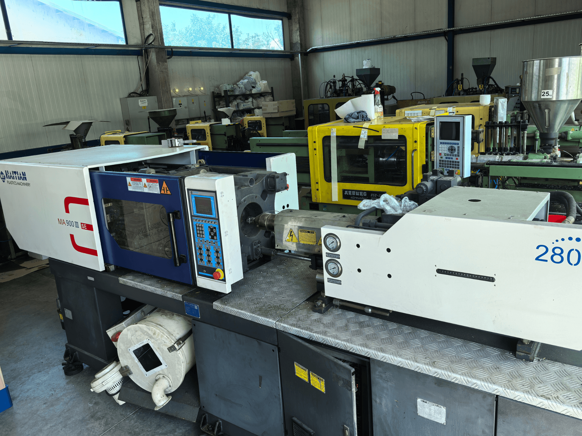 Presse à injection hydraulique HAITIAN MA900ІІ, vue de face, avec le panneau de commande et les composants techniques visibles.