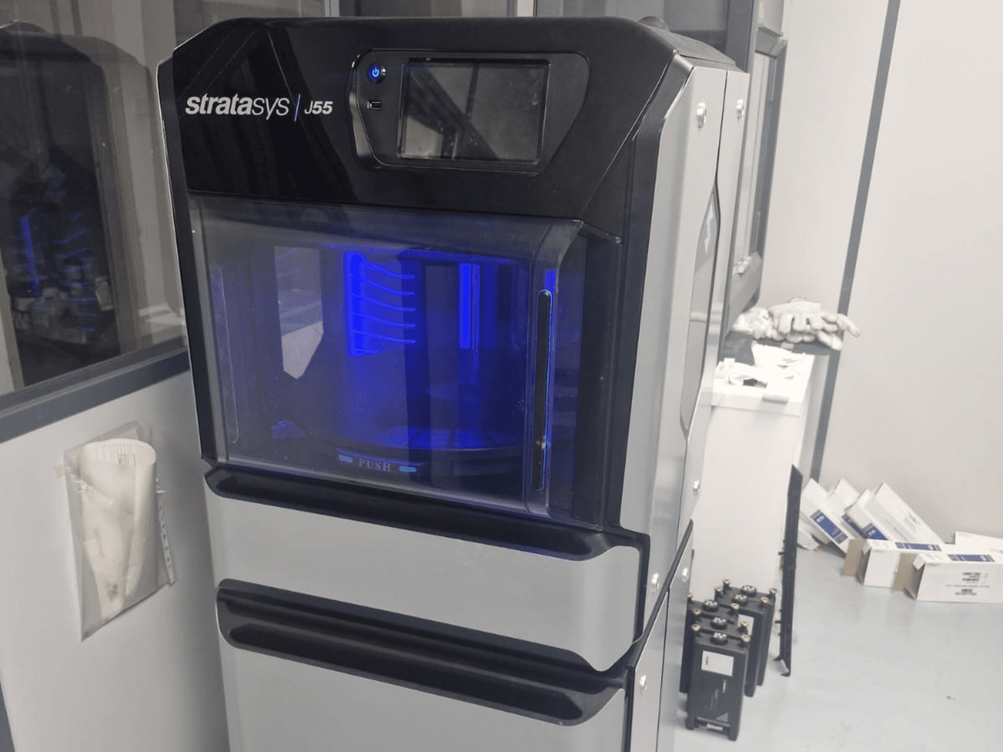 L'imprimante 3D plastique Stratasys J55 Prime vue de côté, montrant son design épuré et sa zone d'impression éclairée.