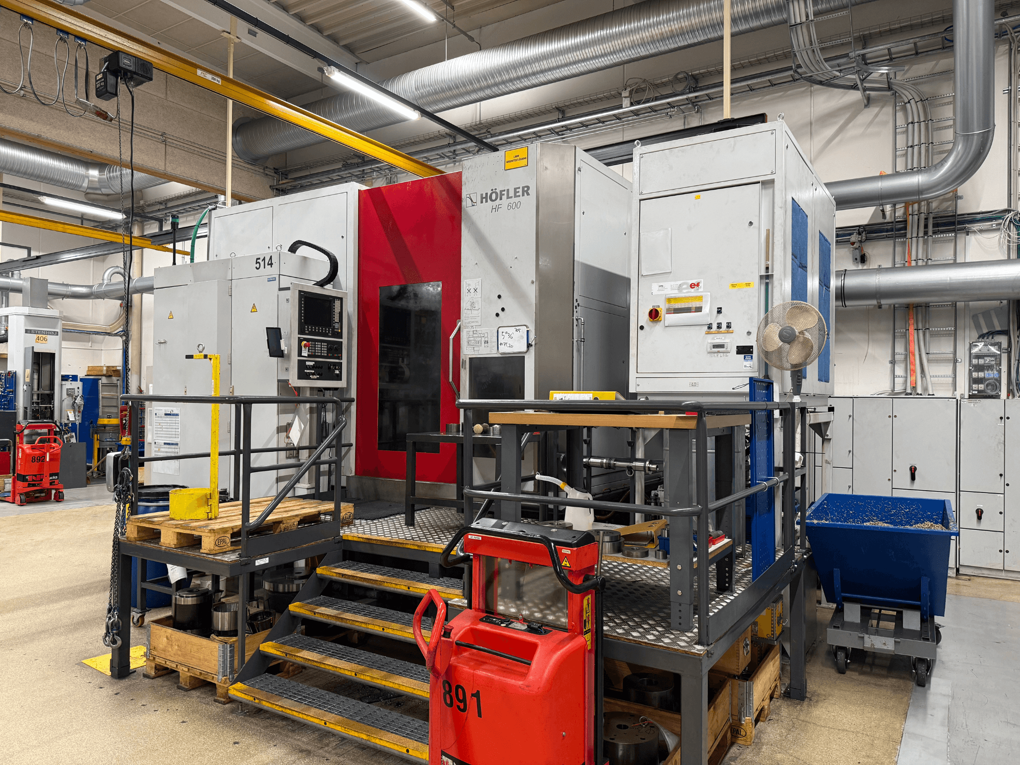 Machine-outil HOFLER HF 600, vue latérale, montrant le panneau de commande, la barrière de sécurité jaune et l'environnement de l'atelier.