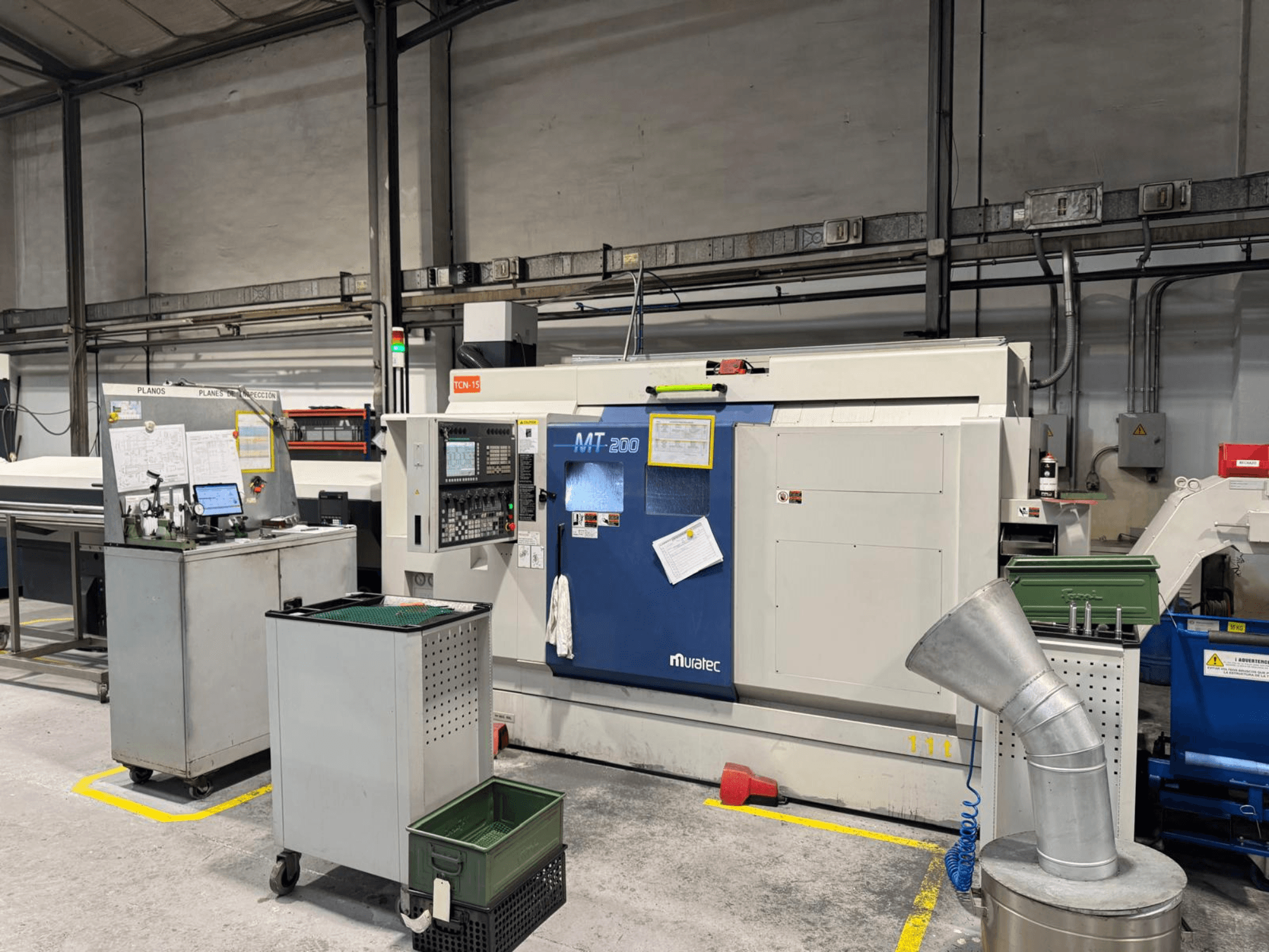 Tour multibroche Muratec MT200 en usine, vu de face, avec le panneau de commande et les équipements environnants.