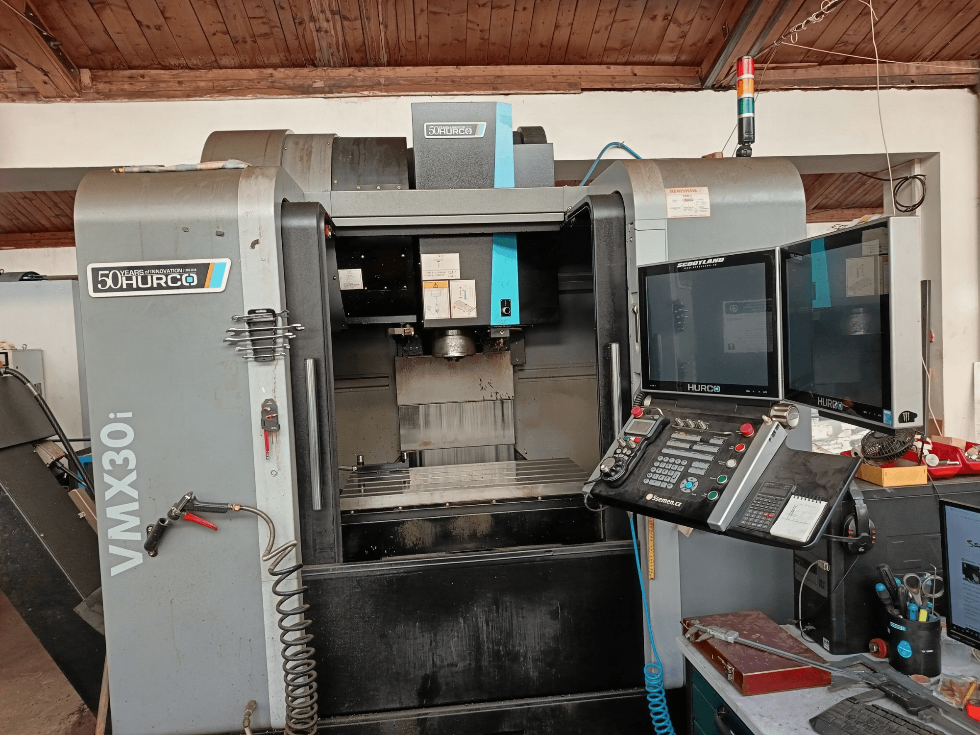 Fraiseuse CNC Hurco VMX30i vue de face, avec deux moniteurs, un panneau de commande et un tuyau attaché.