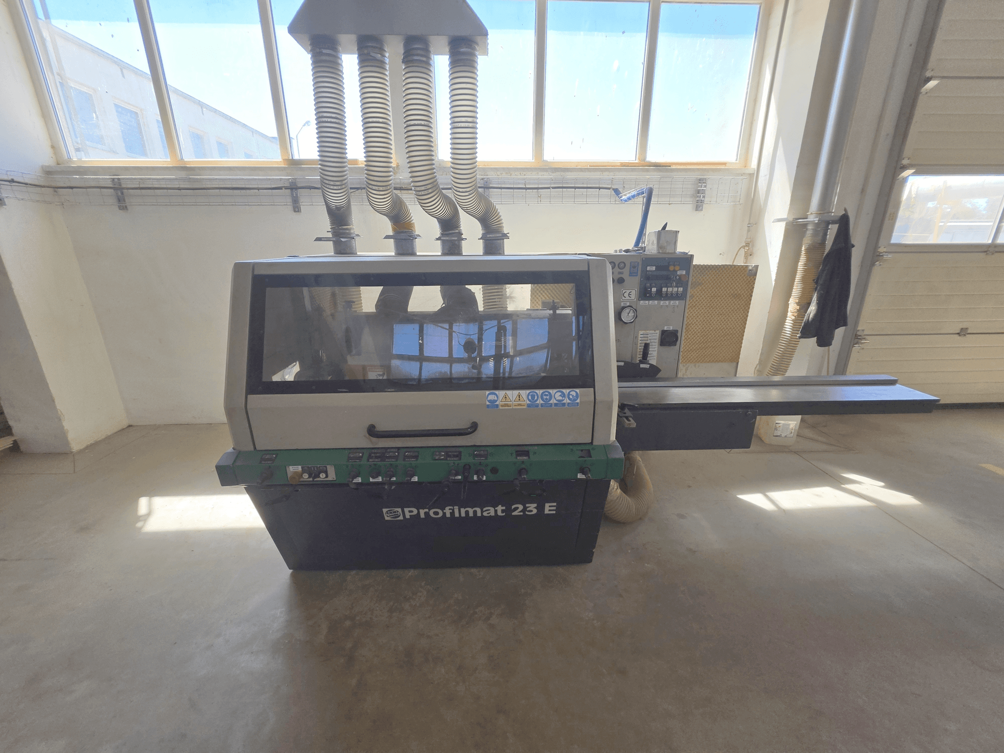 WEINIG DIMTER PROFIMAT 23 E raboteuse à bois, vue de face, comprenant le panneau de commande, la table d'alimentation et les tuyaux d'extraction de la poussière.