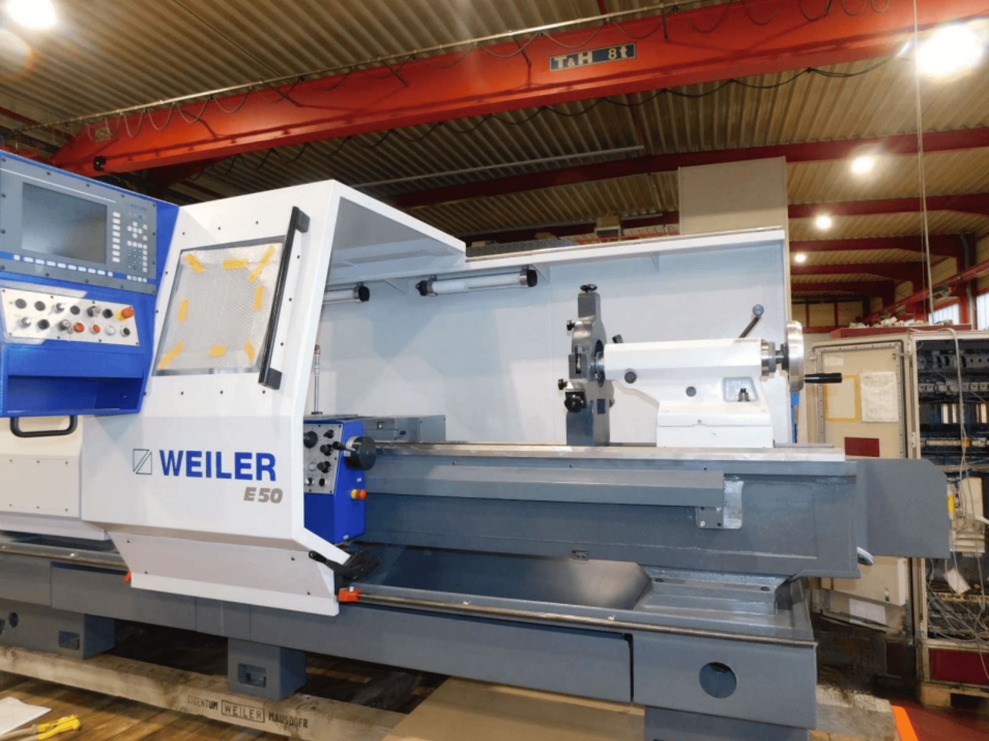 Tour horizontal Weiler E50, vue de face, comprenant le panneau de commande, la broche et le banc de précision avec accessoires.