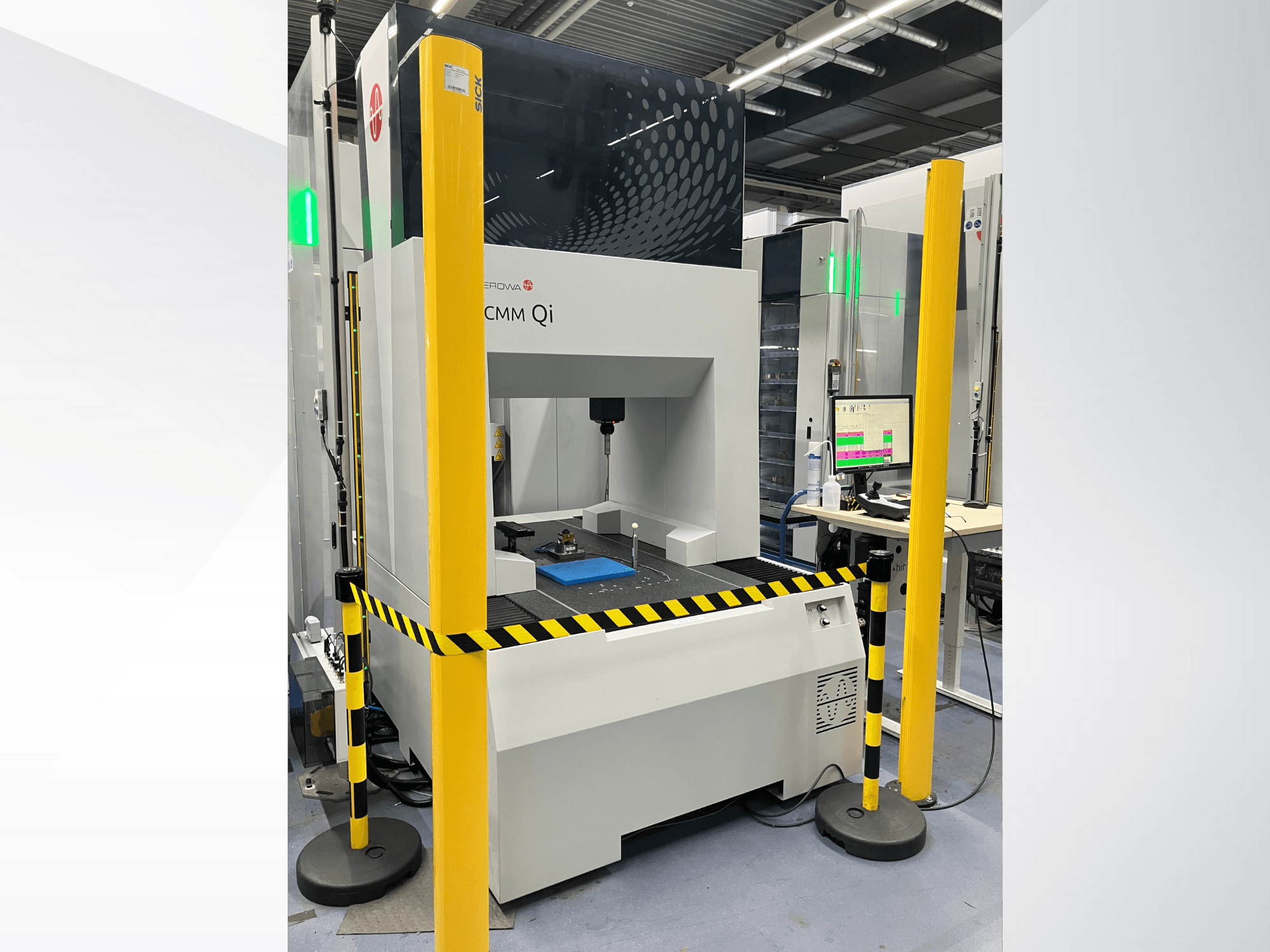 Machine à mesurer tridimensionnelle CMM Qi d'Aerovent, vue de face avec barrières de sécurité et écran affichant les données de mesure.
