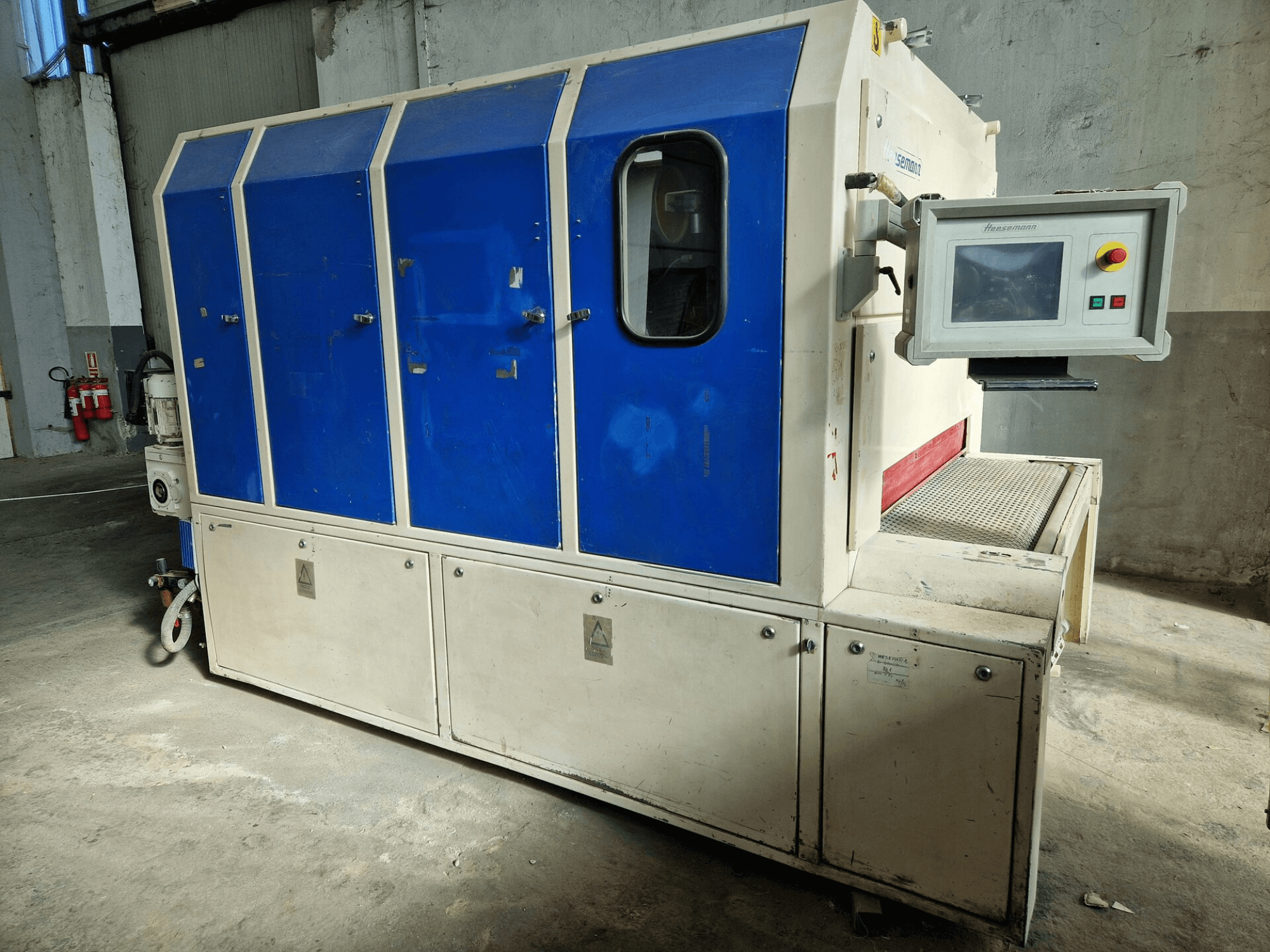 Machine industrielle de la marque "Sedecom", vue de côté ; elle comporte des panneaux bleus, un écran de contrôle et une surface texturée pour la manipulation des produits.