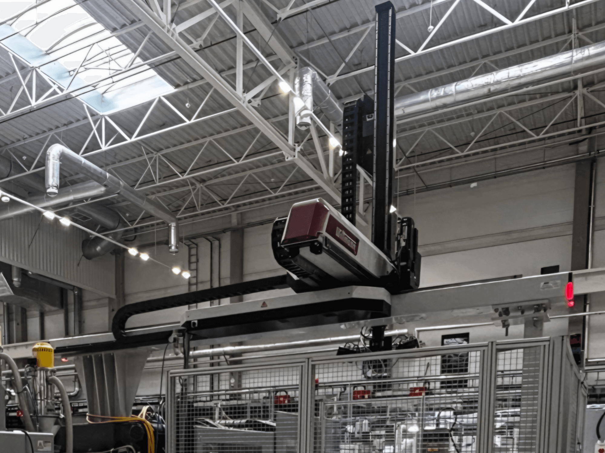 Machine de transformation des matières plastiques WITTMANN W832PRO dans un environnement industriel, vue de profil mettant en évidence le système suspendu et le décor industriel.