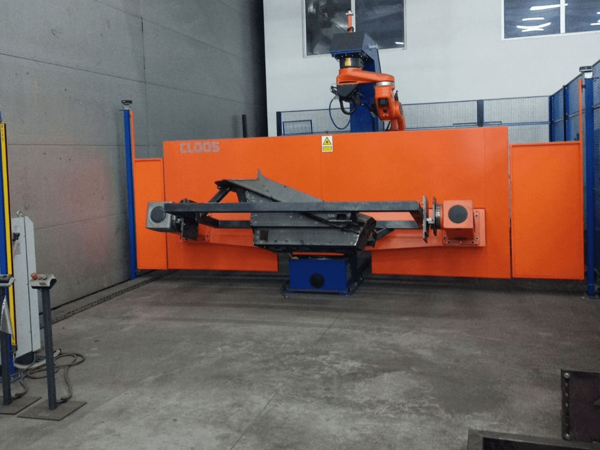 Vue de face du système d'automatisation CLOOS QIROX QRC-350-E avec bras robotique et structure métallique dans un environnement industriel.