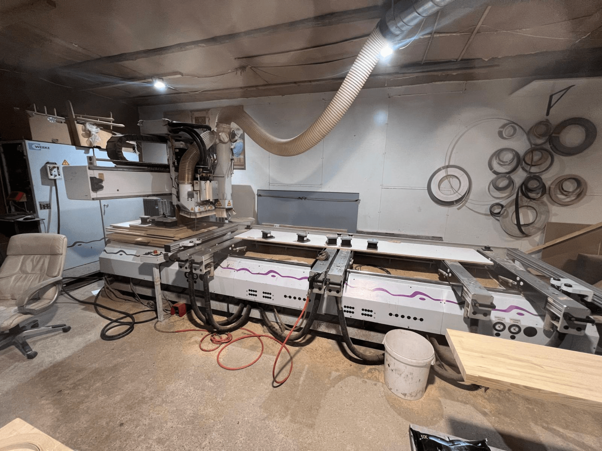 Centre d'usinage CNC pour le bois Weeke OPTIMAT BP 120 dans l'atelier, vue de face avec des pièces de bois et des outils visibles sur la surface.