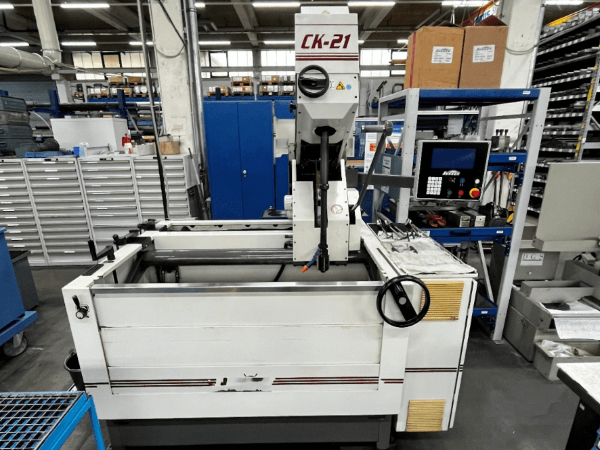 Machine de rodage vertical Sunnen CK-21-CC vue de face, avec en arrière-plan les commandes, la zone de rodage et l'équipement auxiliaire.