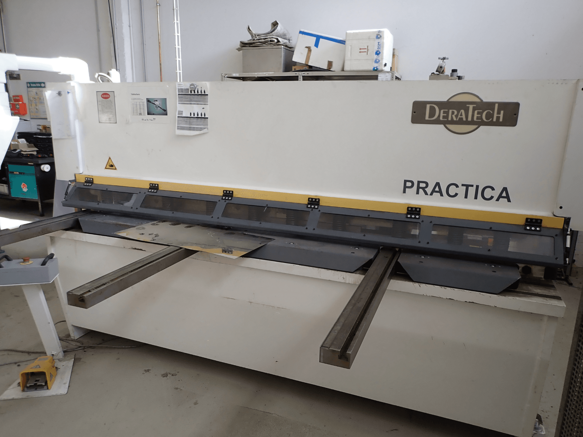 Machine à cisailler DERATECH Practica CNC, vue de face, montrant la lame de coupe et les tôles sur la surface de travail.