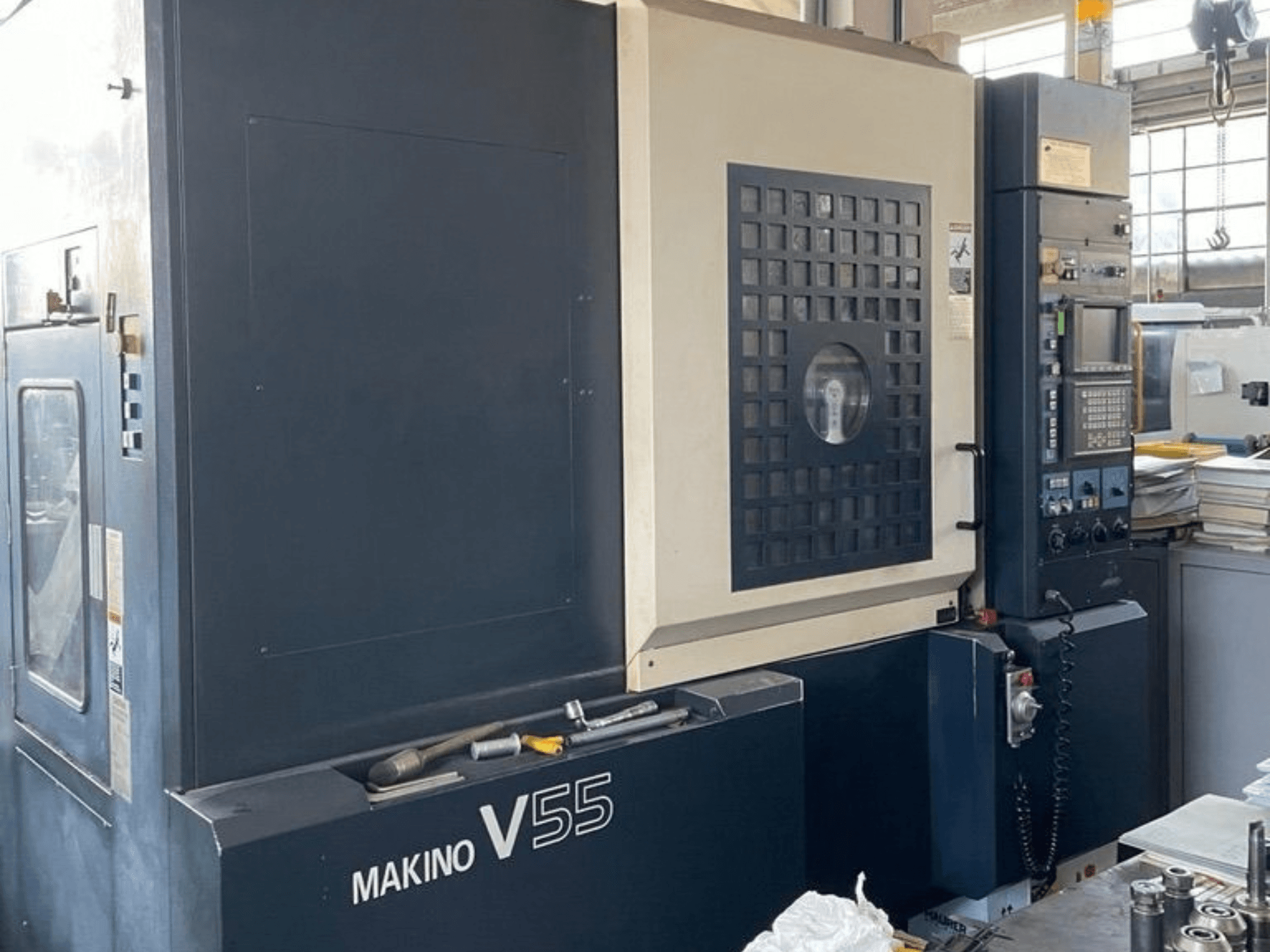 Centre d'usinage vertical Makino V55-A15, vue de face montrant le panneau de commande, la construction robuste et la configuration de l'espace de travail.