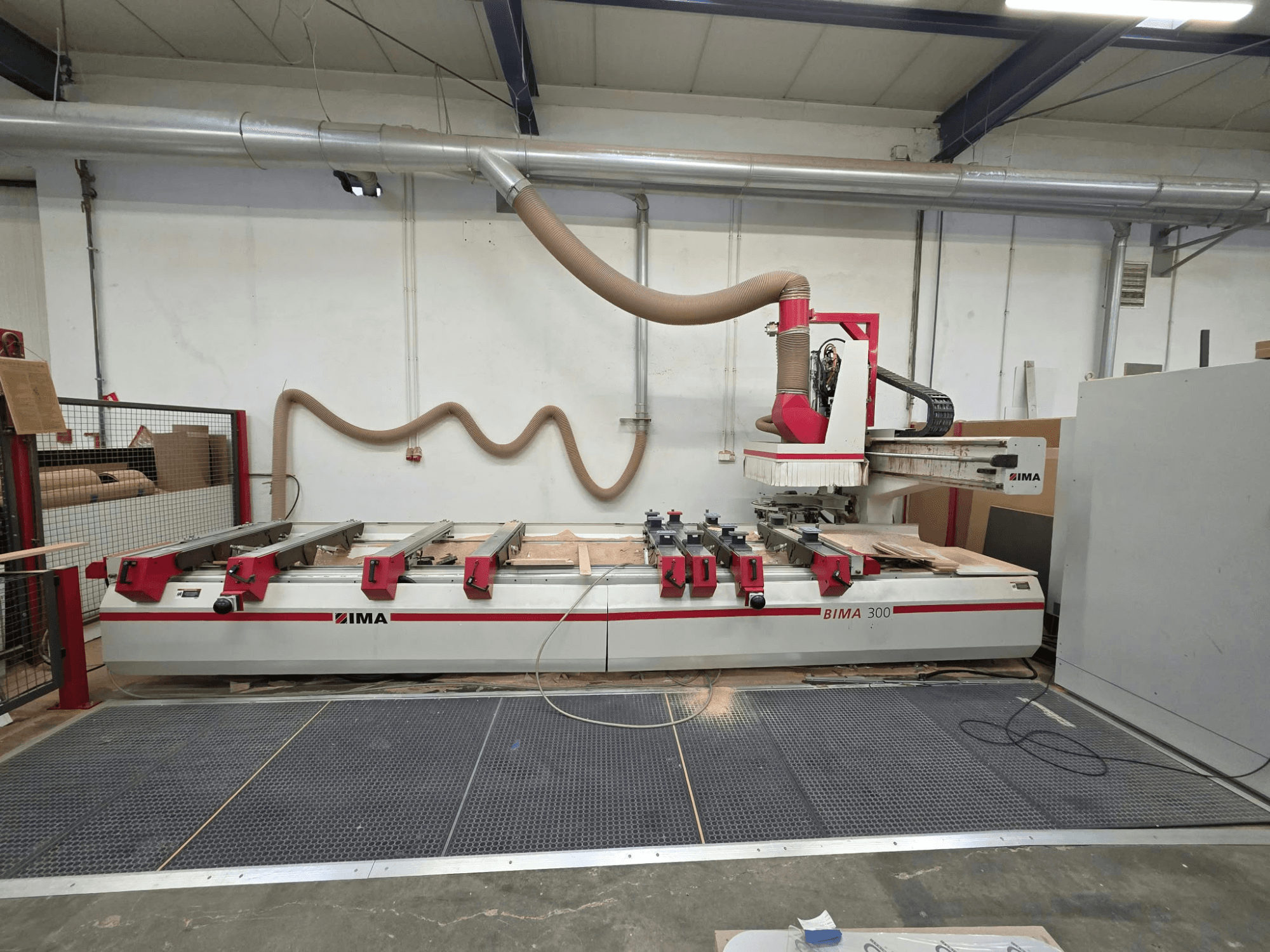 Centre d'usinage CNC pour le bois IMA BIMA 300, vue de face, équipé d'un outil multiaxial et d'un système d'aspiration des poussières.