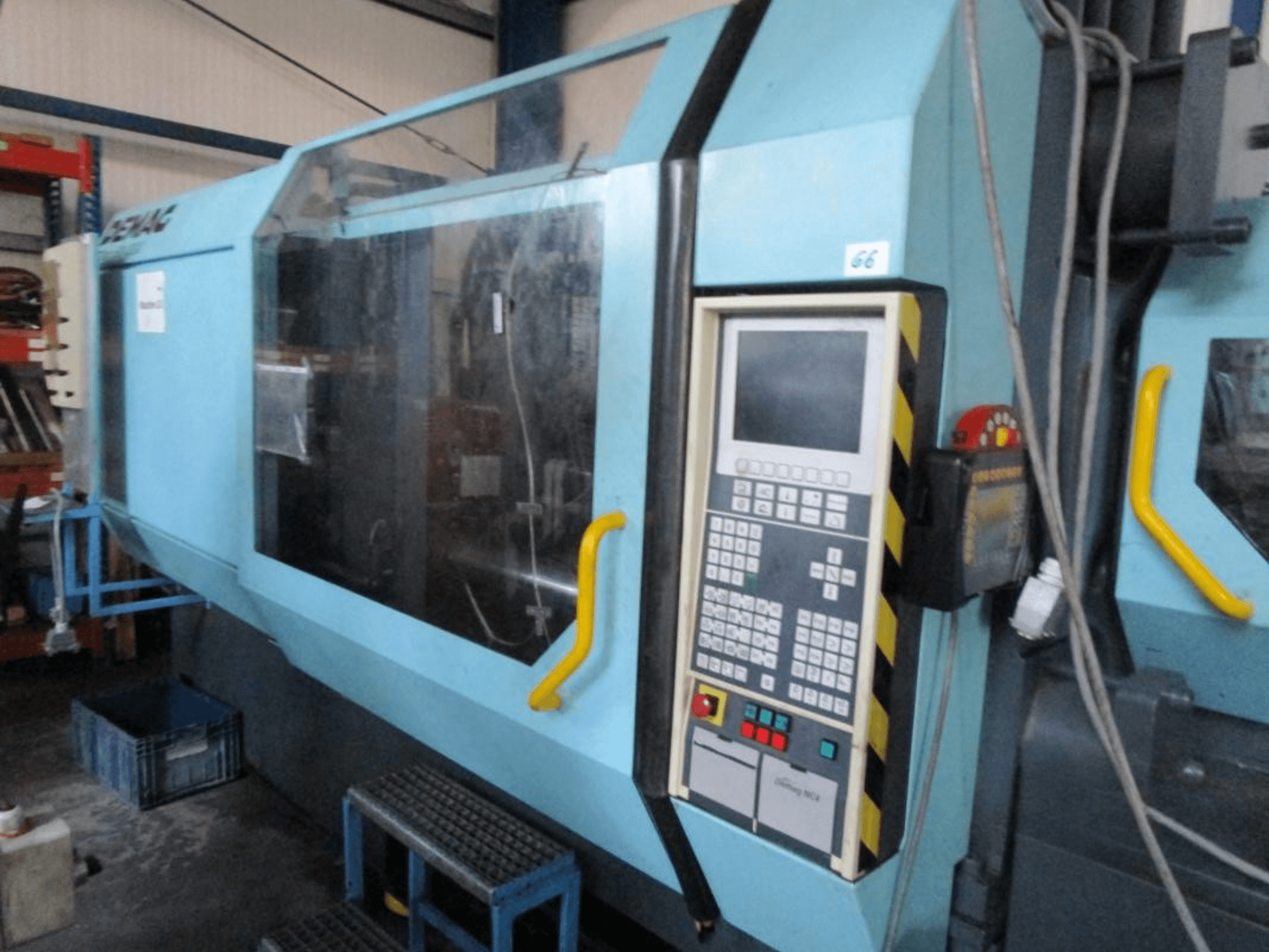 Machine de moulage par injection hydraulique Demag Erdotech 500-3300, vue de face, dotée d'un panneau de commande et d'une enceinte de sécurité transparente.
