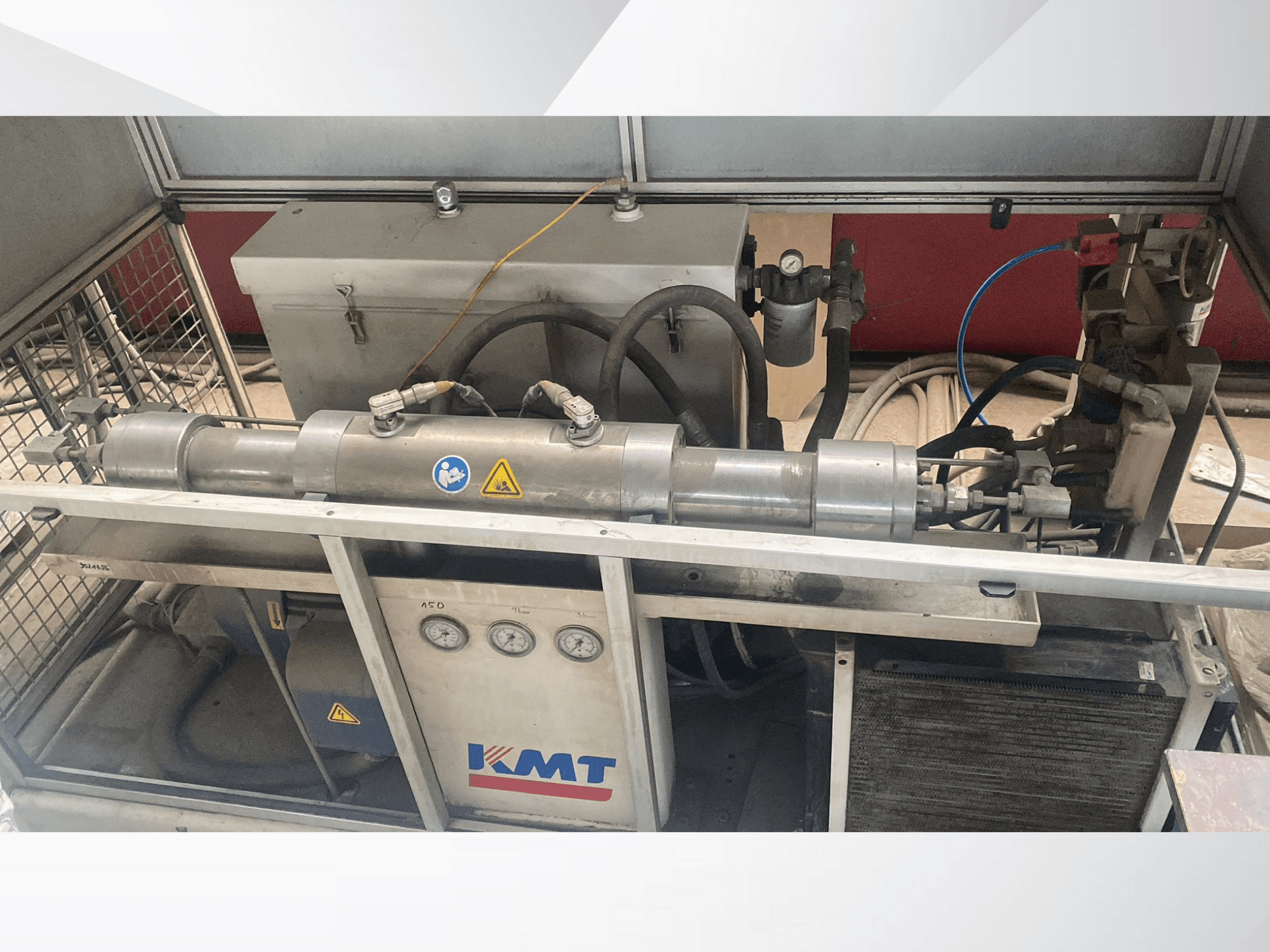 Machine hydraulique KMT vue de face, équipée de manomètres, de tuyaux et d'un carter métallique, idéale pour les applications industrielles.