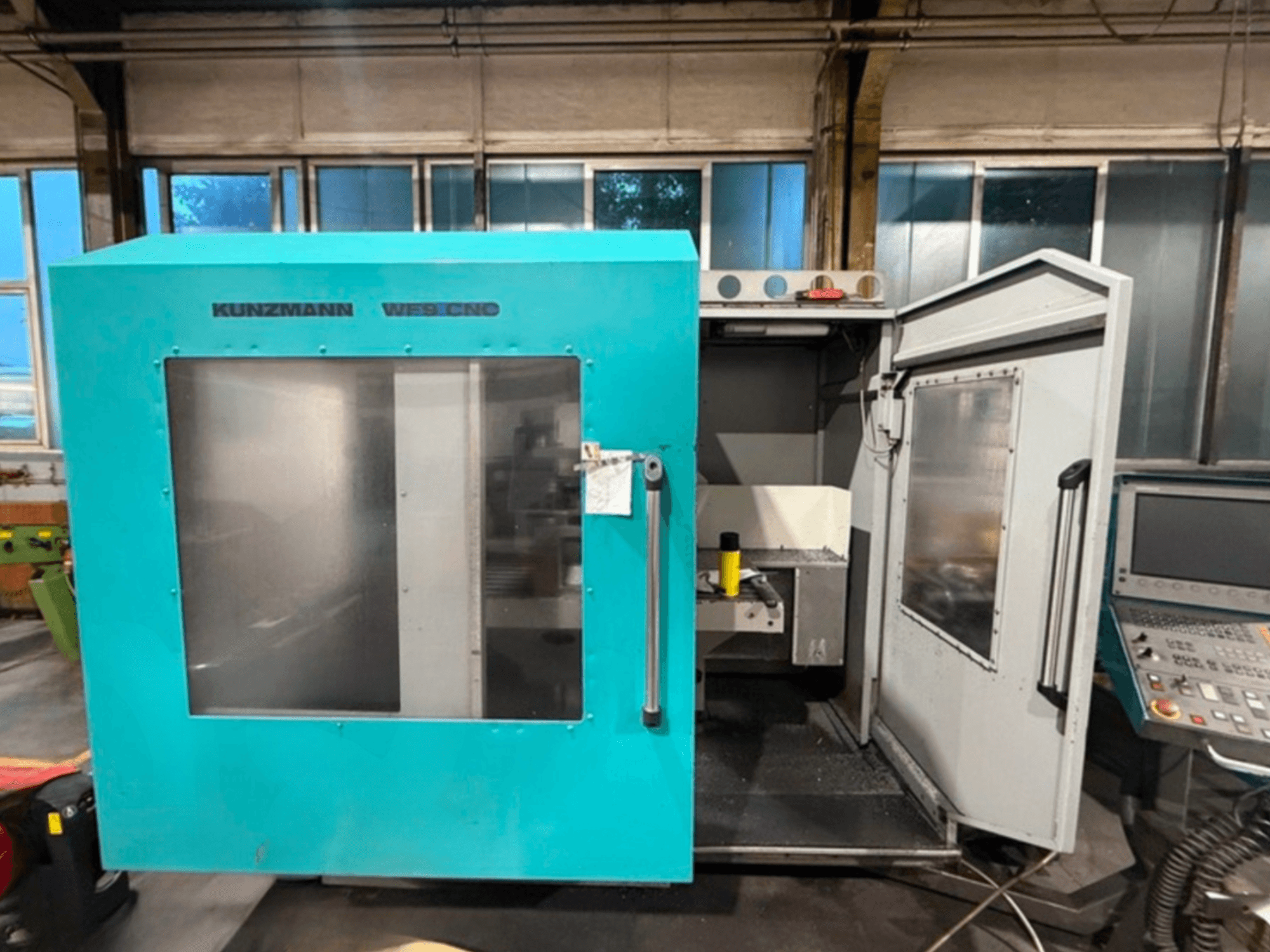 Centre d'usinage vertical CNC WF9 de KUNZMANN, vue de face avec les portes ouvertes, montrant l'intérieur et le panneau de commande.