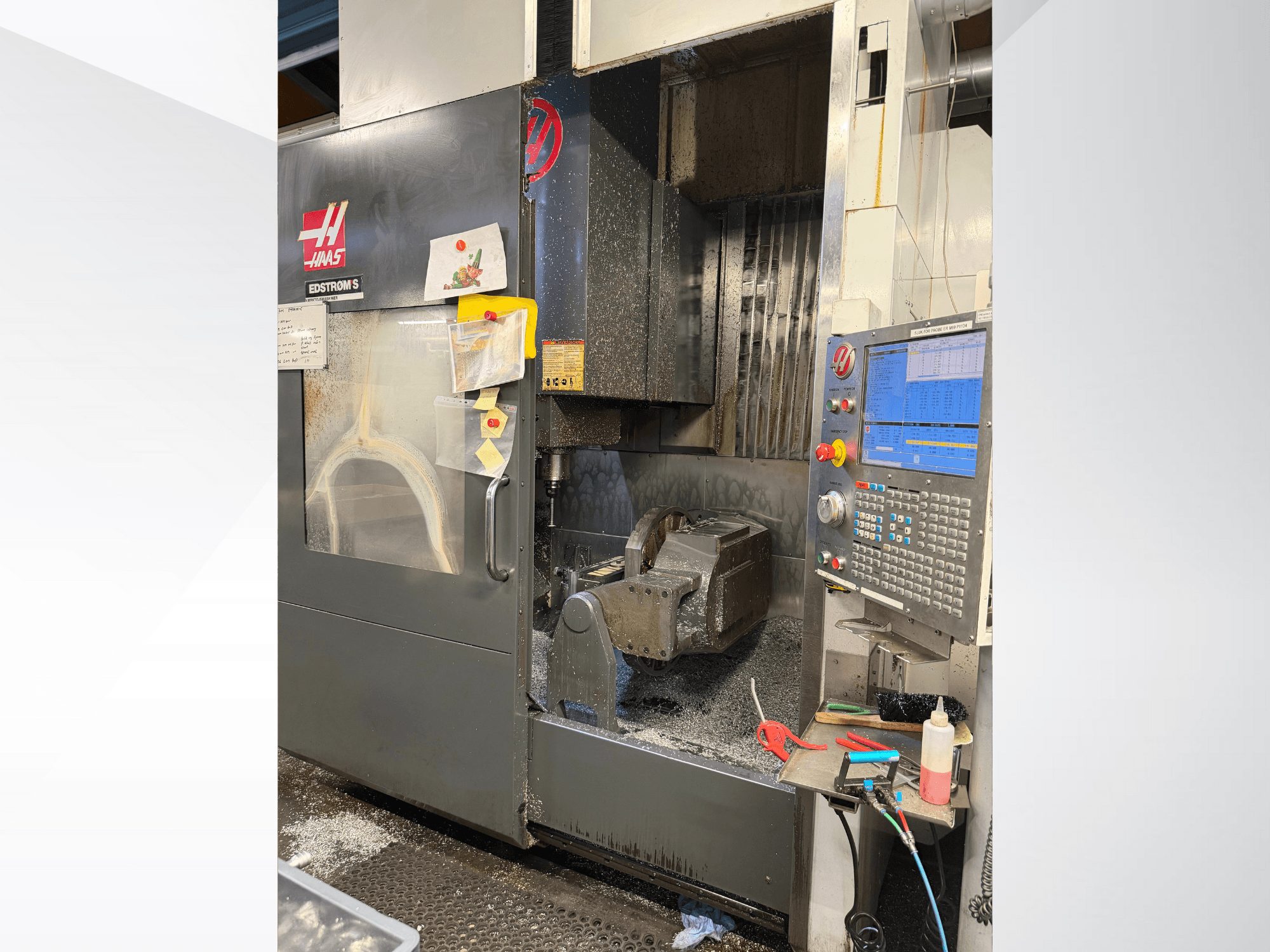 Machine CNC Haas modèle EDSTROM S, vue de face, montrant la pièce métallique, le panneau de commande et les copeaux de métal à l'intérieur.