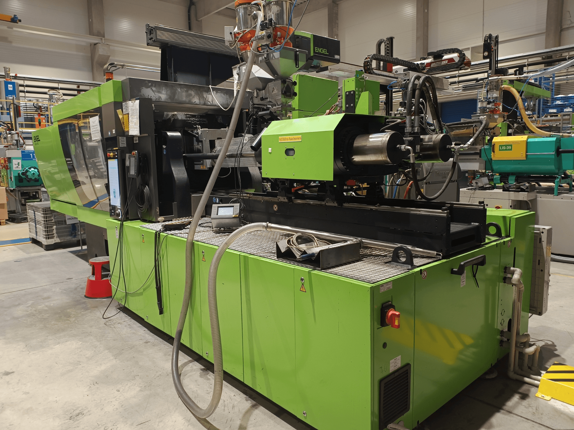 Machine de moulage par injection Engel, vue latérale, extérieur vert, avec écran tactile et composants hydrauliques visibles.