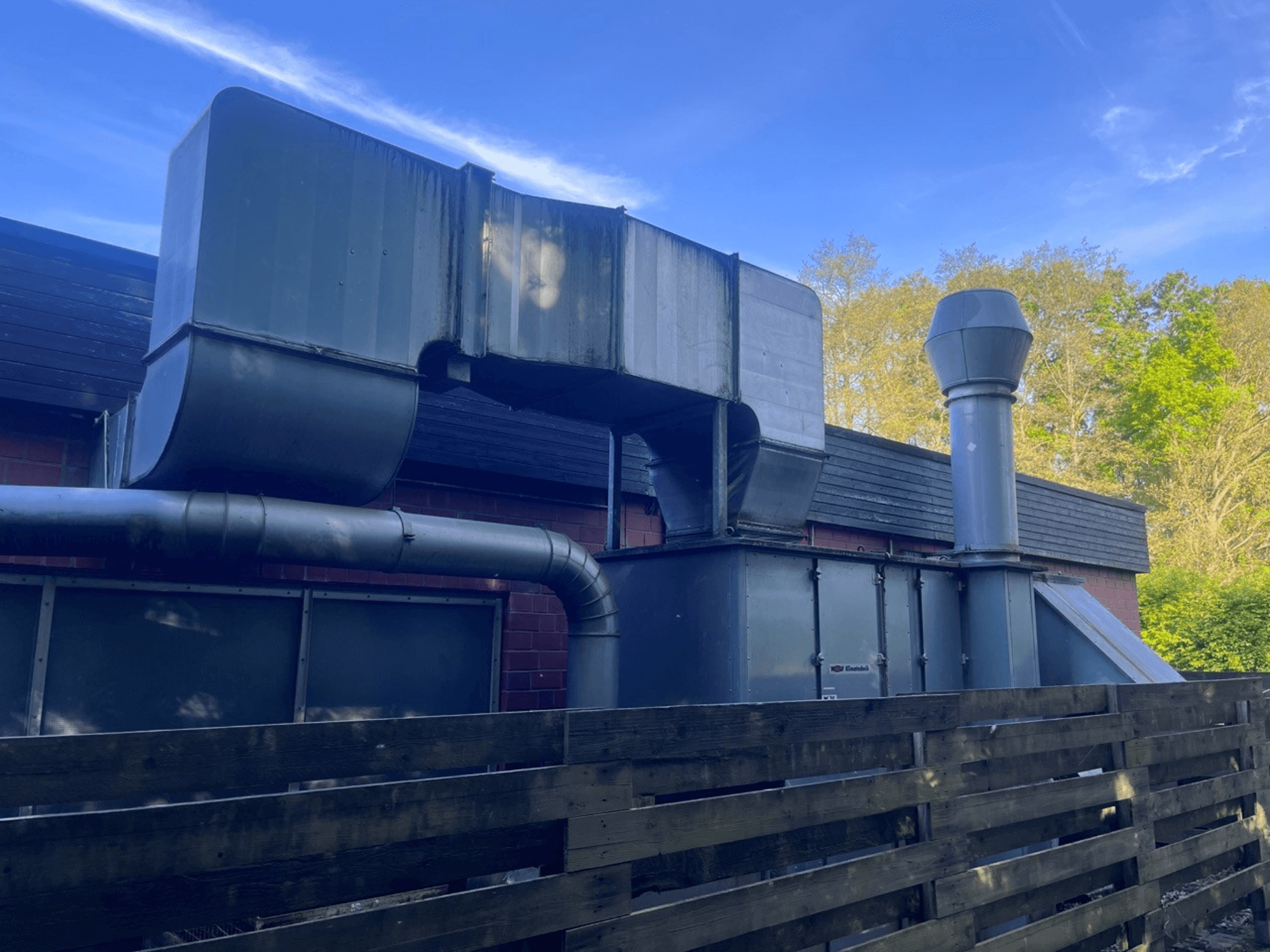 Système de ventilation industrielle avec conduits métalliques, vue latérale ; comprend une cheminée carrée et cylindrique, finition verte.