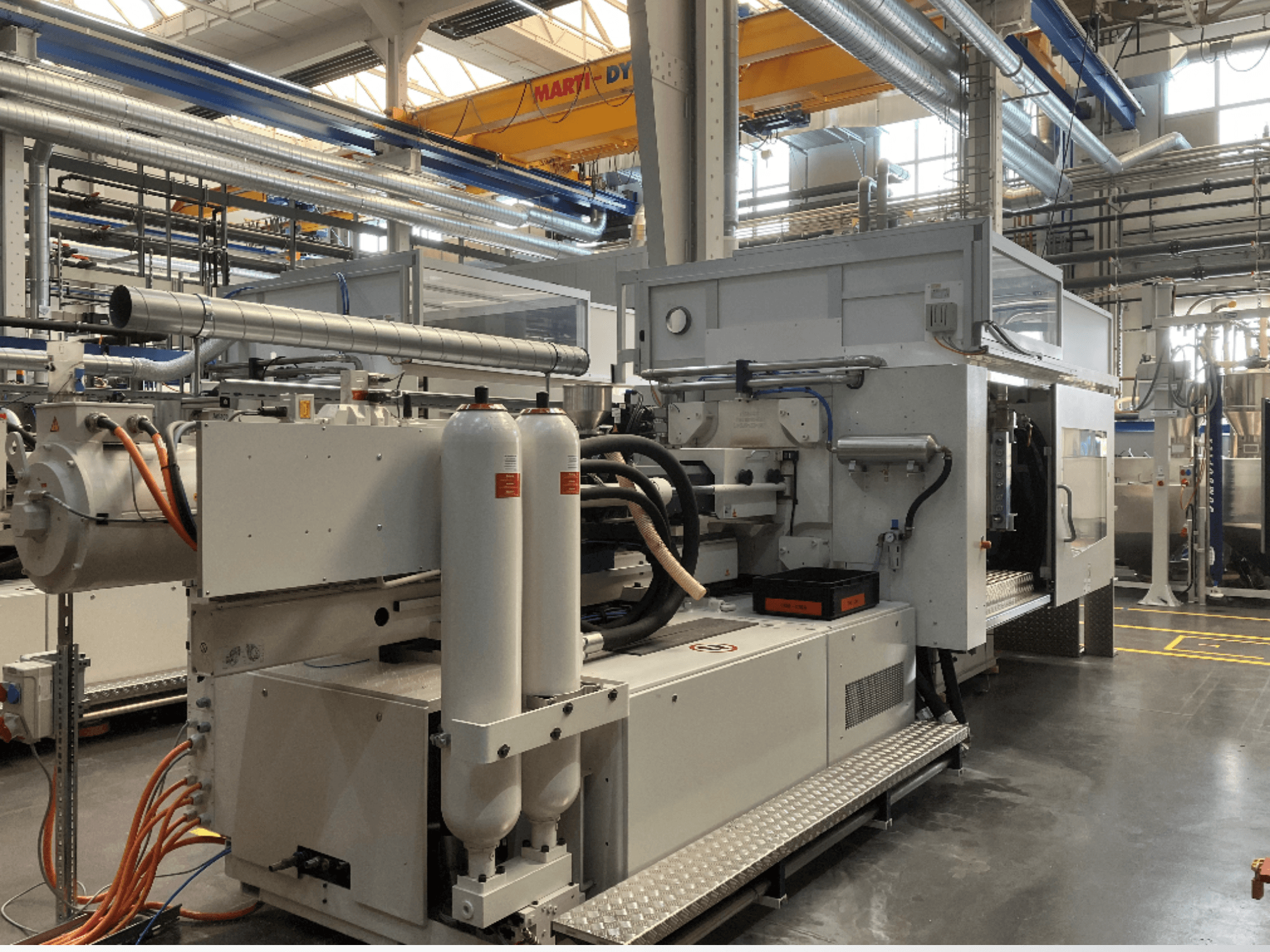 Machine industrielle présentée en vue latérale avec plusieurs tuyaux, deux réservoirs verticaux et un panneau de commande ; la marque/le modèle n'est pas visible.