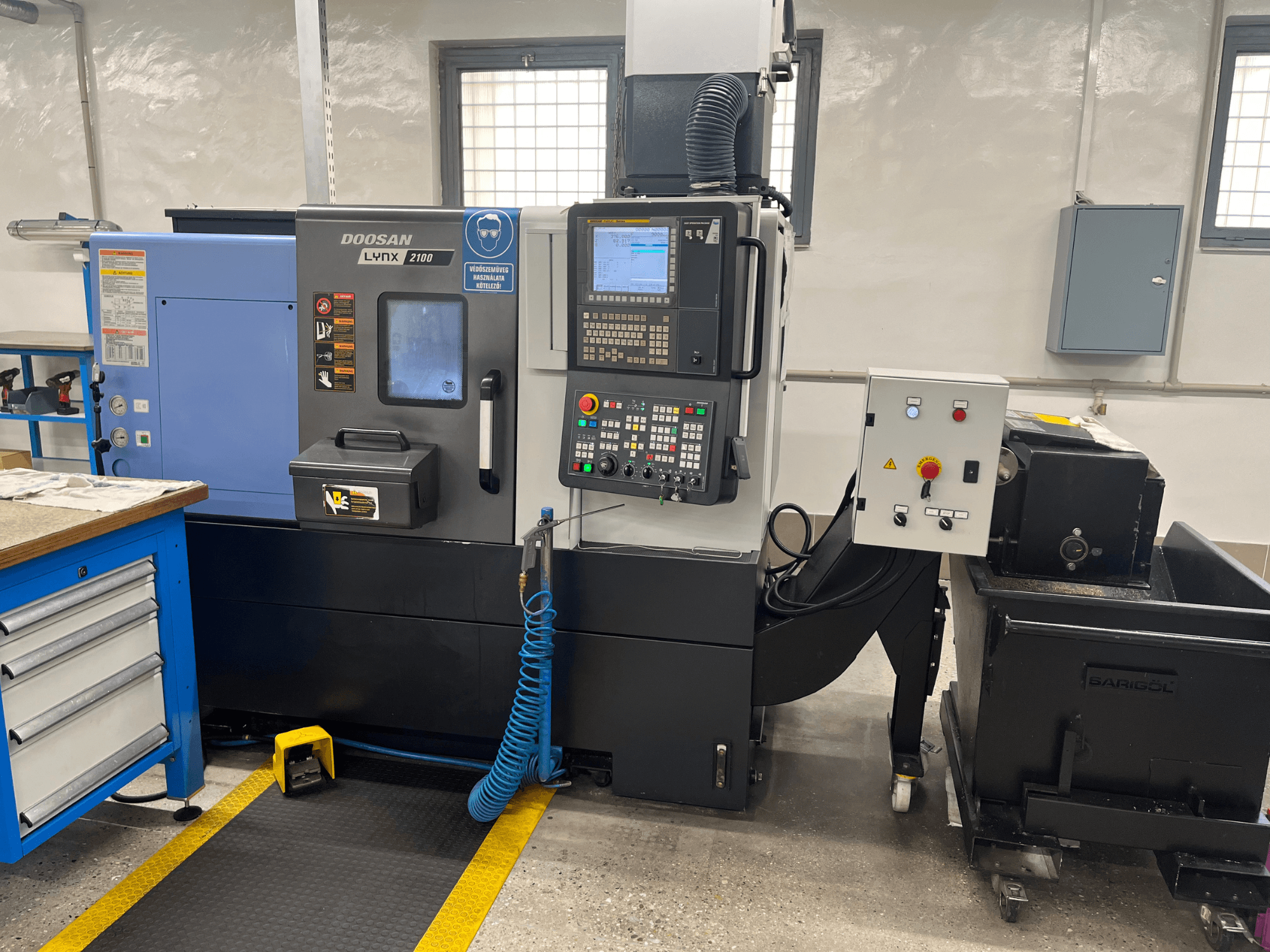 Tour Doosan Lynx 210 dans l'atelier, montrant le panneau de commande, le stockage des outils et le système de refroidissement, vue latérale avec détails de l'espace de travail.