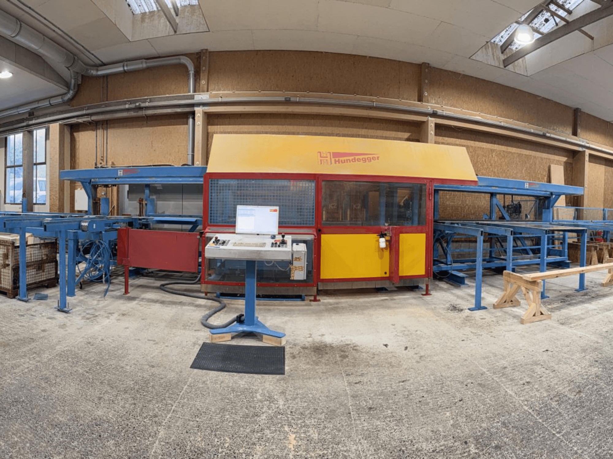 Vue de face de la ligne complète de production de bois HUNDEGGER K2-4-450, comprenant un panneau de commande et un système de convoyage.