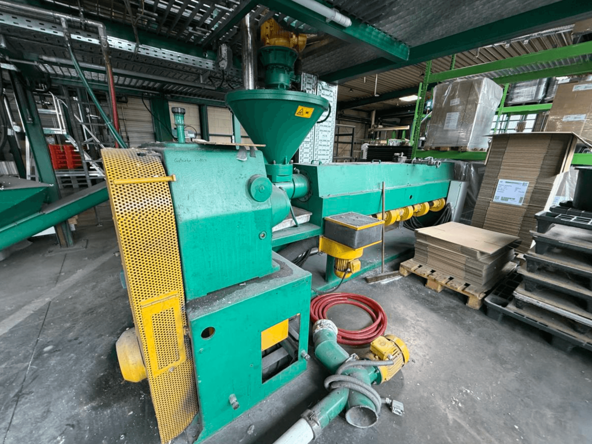 Extrudeuse monovis Prealpina 105 de la marque « Other », vue de profil ; elle présente un carter vert, des accessoires de convoyage et des matériaux à proximité.