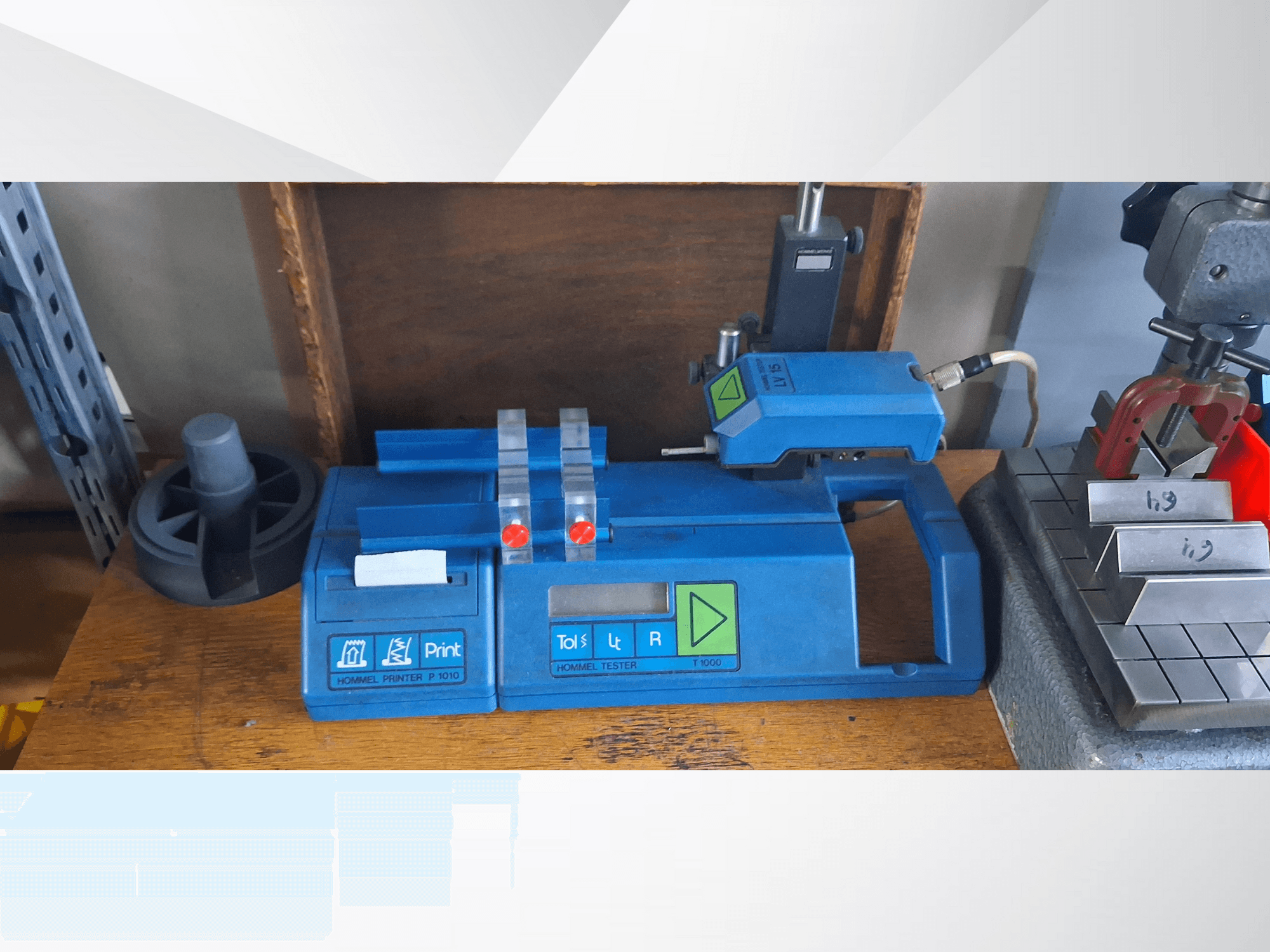 Imprimante Hommel T 1000 bleue et testeur T 1 010 avec boutons rouges, vus de face sur un établi avec des blocs métalliques.