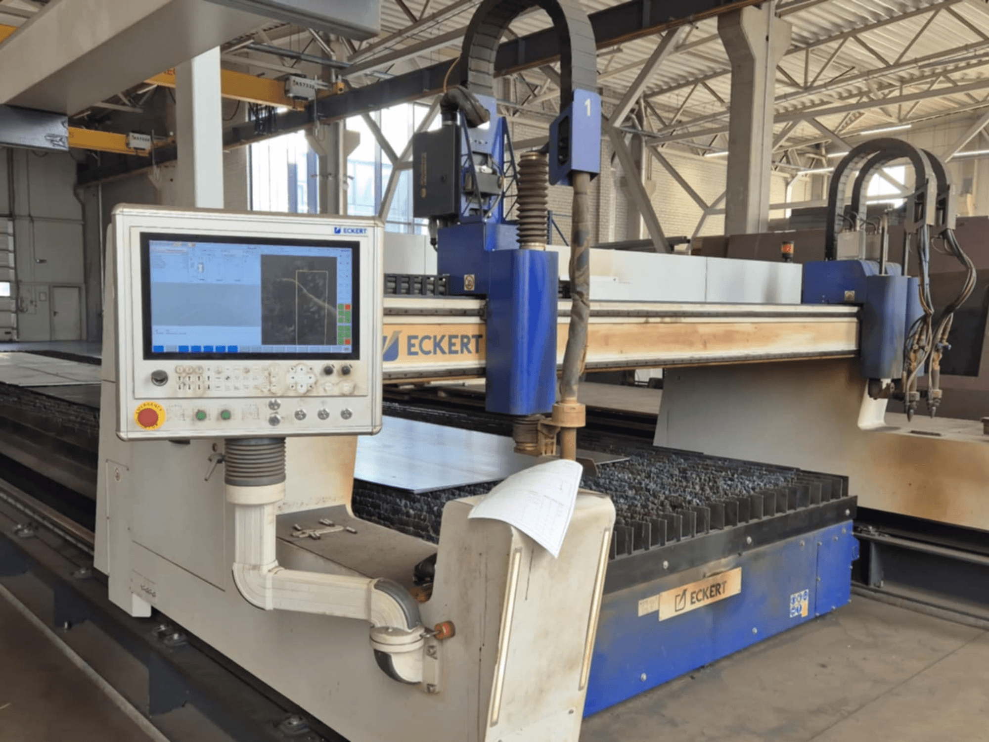 Panneau de commande de la machine de découpe CNC ECKERT en vue de face, comportant un écran tactile et divers boutons de commande.