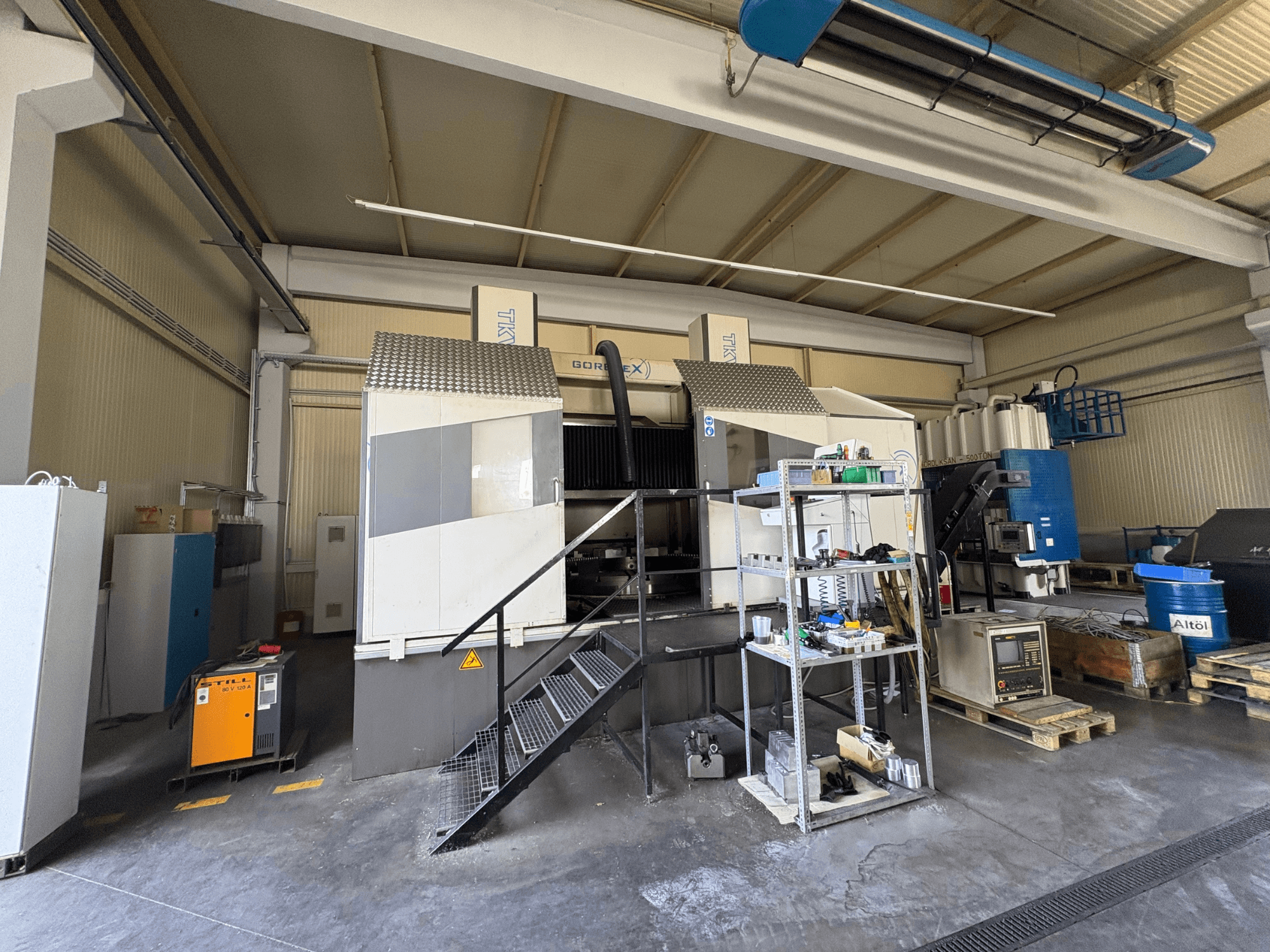 Installation d'usinage industriel avec la machine GORAT X, vue latérale ; comprend les outils, le panneau de commande et l'équipement sur les étagères.