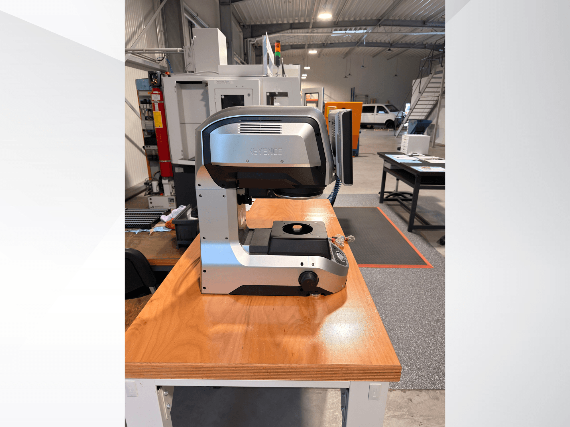Vue de face de la machine de mesure optique KEYENCE IM-8005 posée sur une table en bois, mettant en valeur son design épuré et son interface utilisateur.