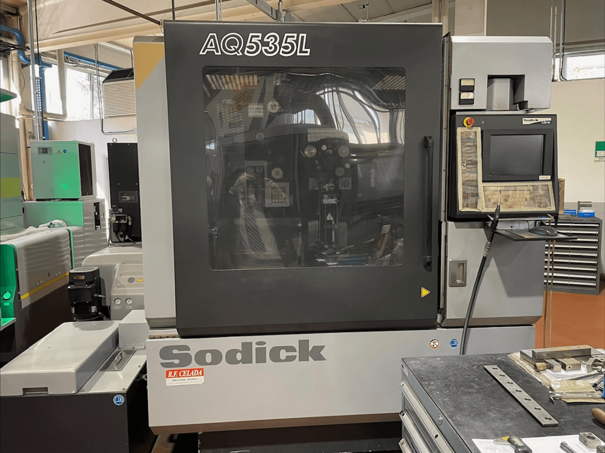 Vue avant de la machine d'électroérosion à fil Sodick AQ535L, avec le panneau de commande et le capot de protection transparent.
