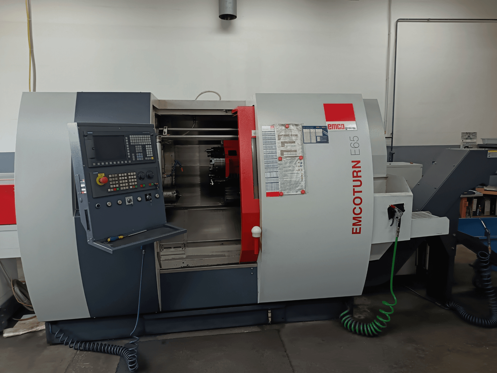 Centre de tournage-fraisage EMCO EMCOTURN E65, vue de face montrant le panneau de commande, le mécanisme interne et les caractéristiques dans un atelier.