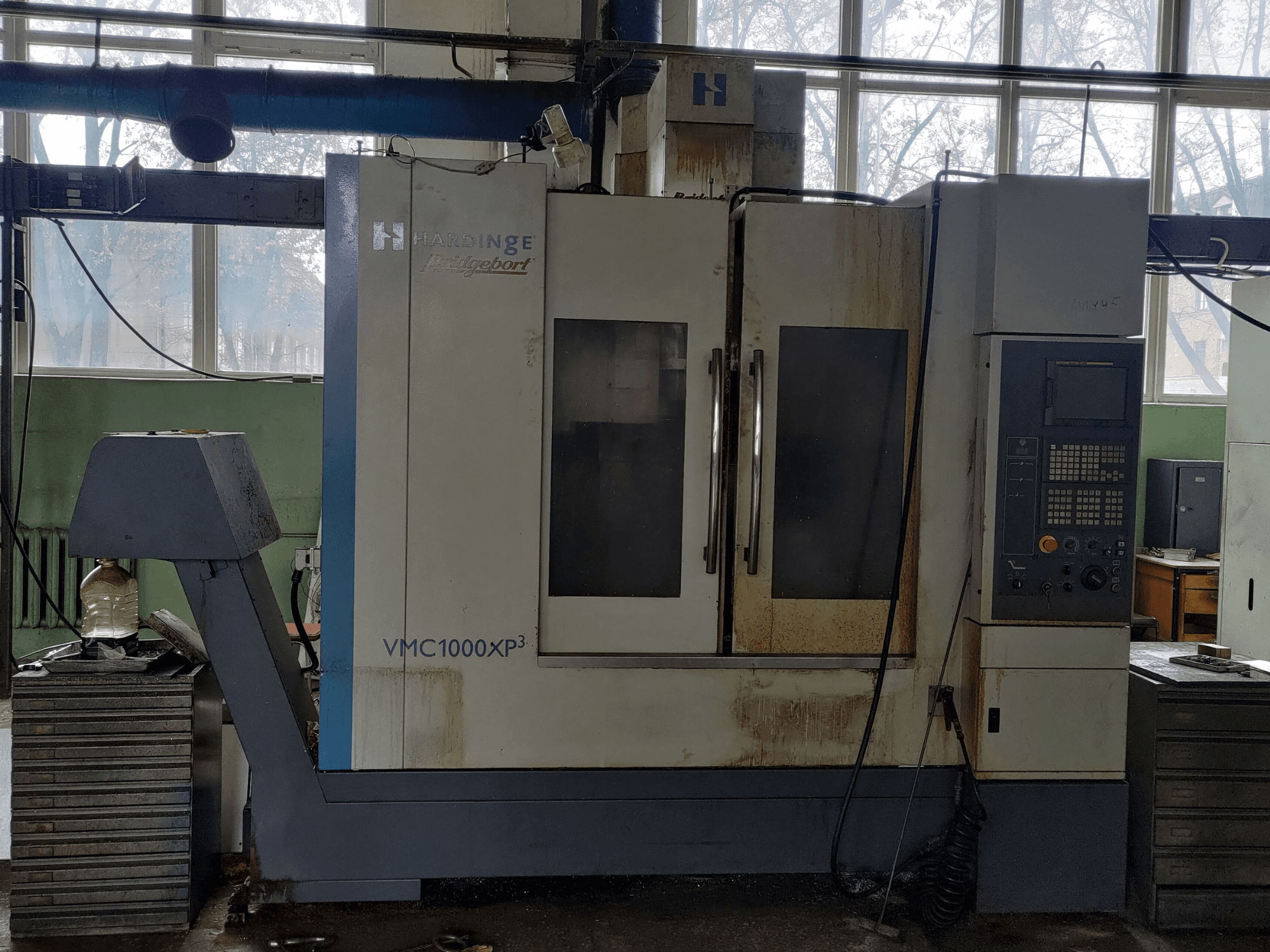 Centre d'usinage vertical Bridgeport VMC1000 XP3 vu de face, montrant le panneau de commande et de légères traces d'usure.