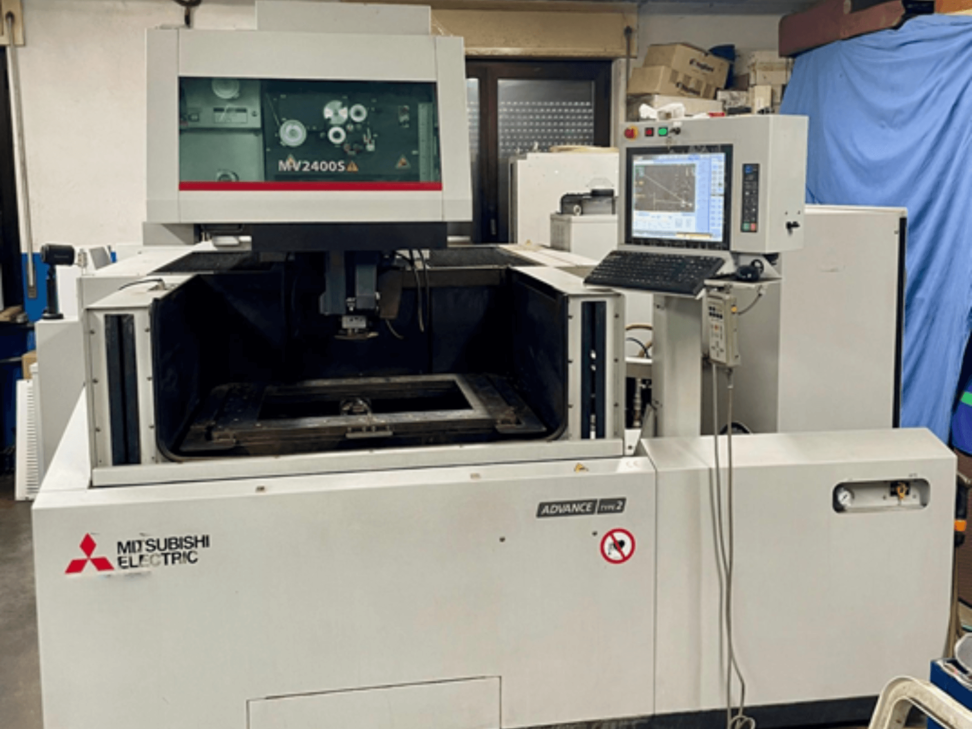 Machine d'électroérosion à fil Mitsubishi MV 2400S, vue de face, avec un panneau de commande et une zone de travail visible pour la découpe de précision.