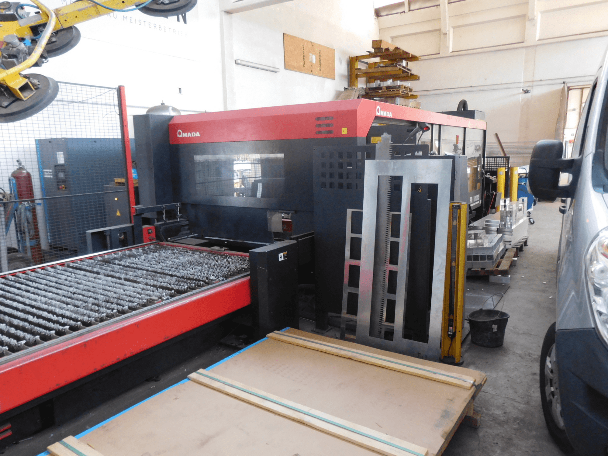 Vue de face de la machine de découpe laser CO2 AMADA FO-3015 II RI, comprenant un banc de découpe et la zone de travail environnante.