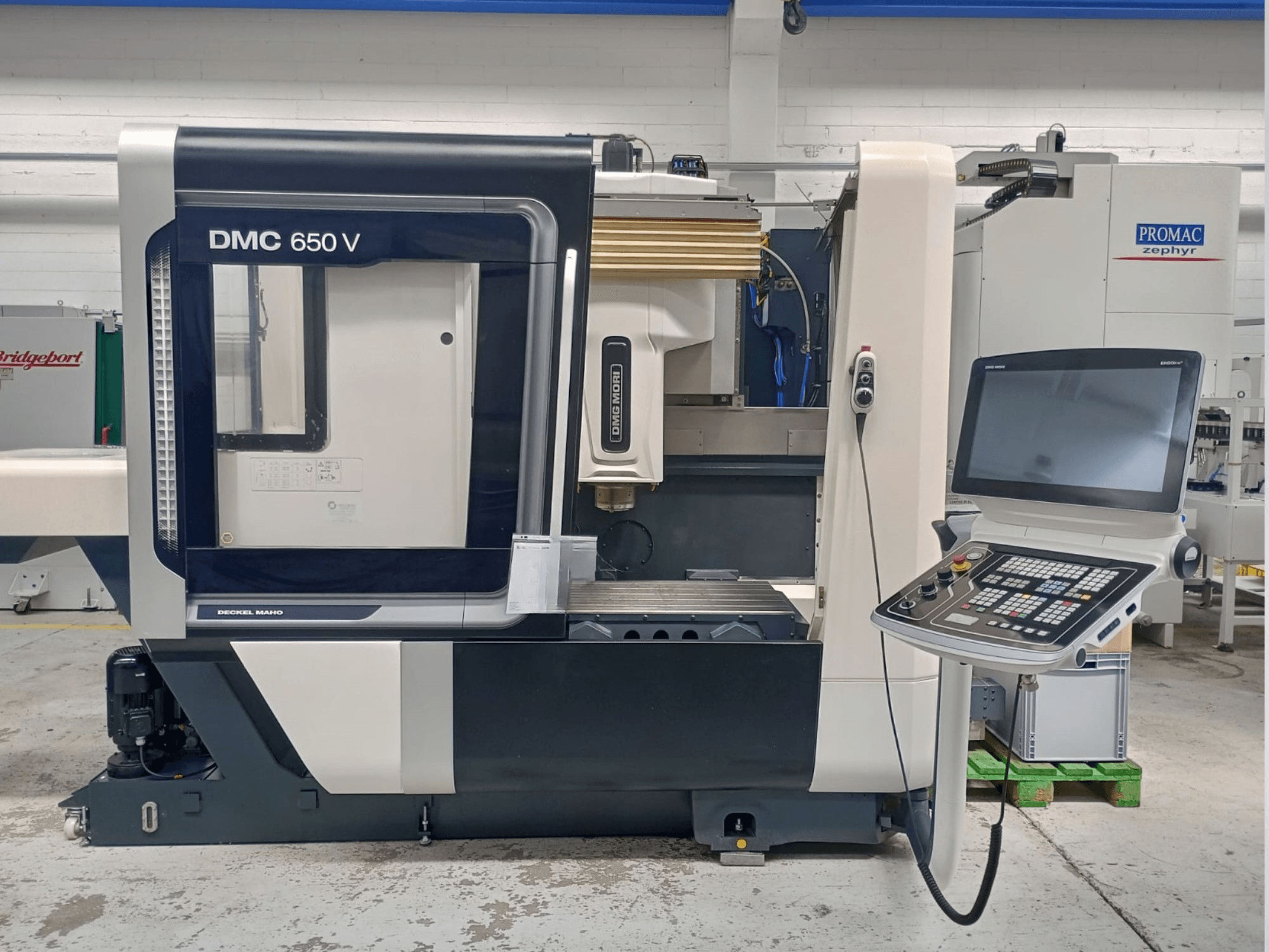 Machine CNC Decker Maho DMC 650 V vue de côté, comportant un panneau de commande avec des boutons et un écran, dans un environnement industriel.