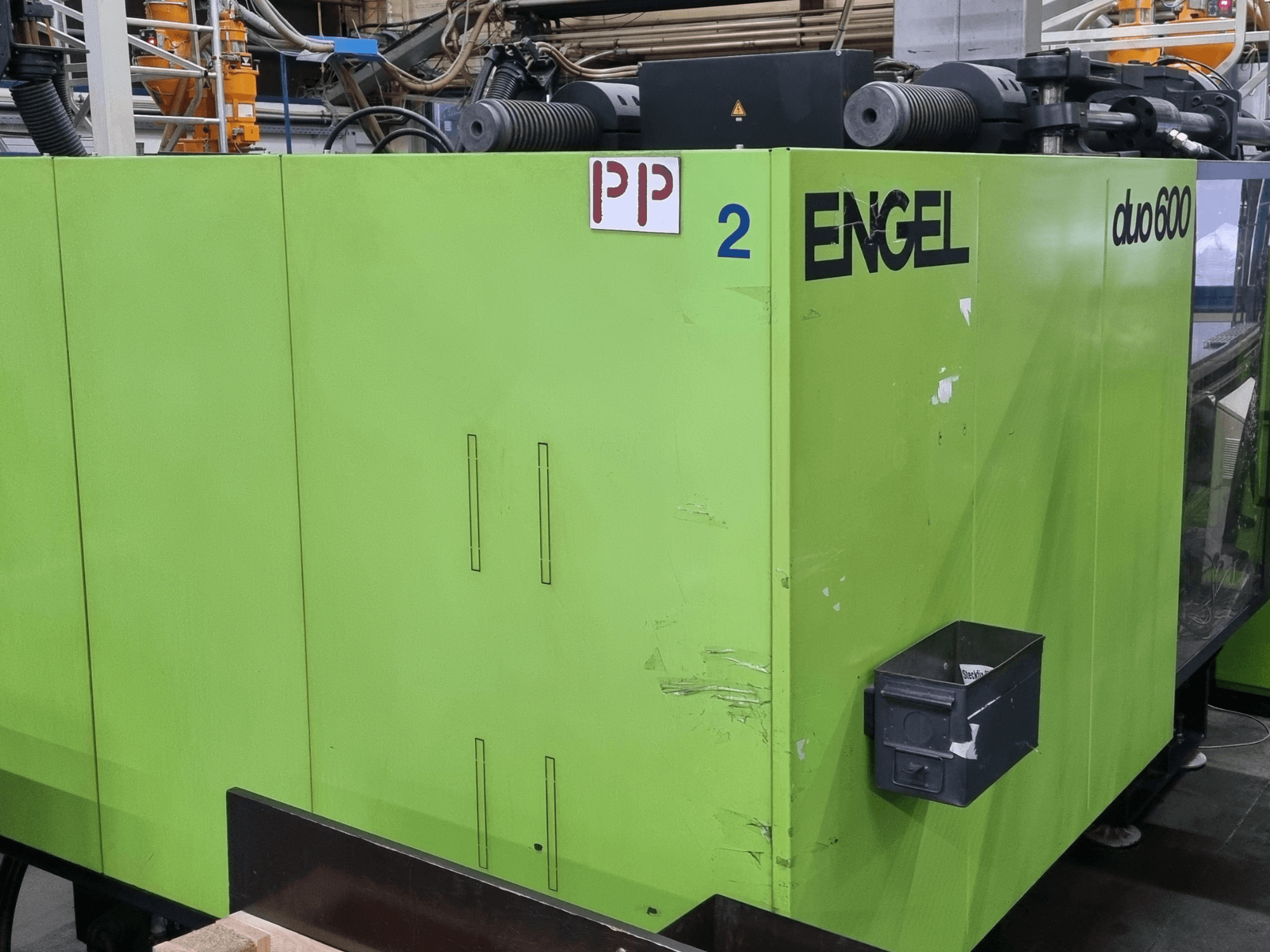 Presse à injection hydraulique Engel Duo 600, couleur verte, vue de face, avec les pièces identifiées et un bac de rangement pour les matériaux.