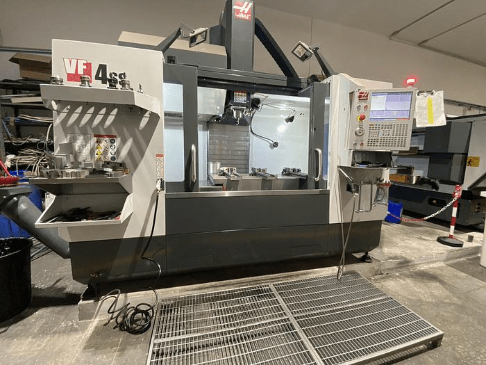 Fraiseuse CNC Haas VF-4SS, vue de face, avec rangement des outils, panneau de commande et zone de travail visible dans un atelier.