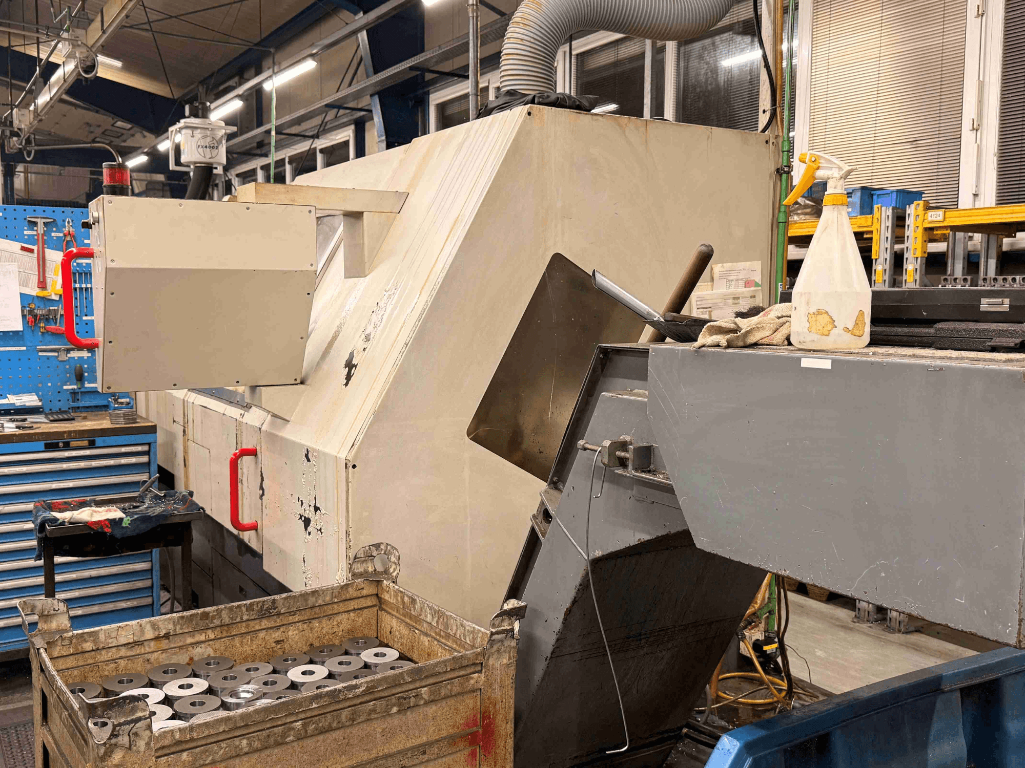 Tour horizontal à commande numérique ZPS S-60 dans un atelier, vu de profil avec les pièces à usiner et les commandes visibles.