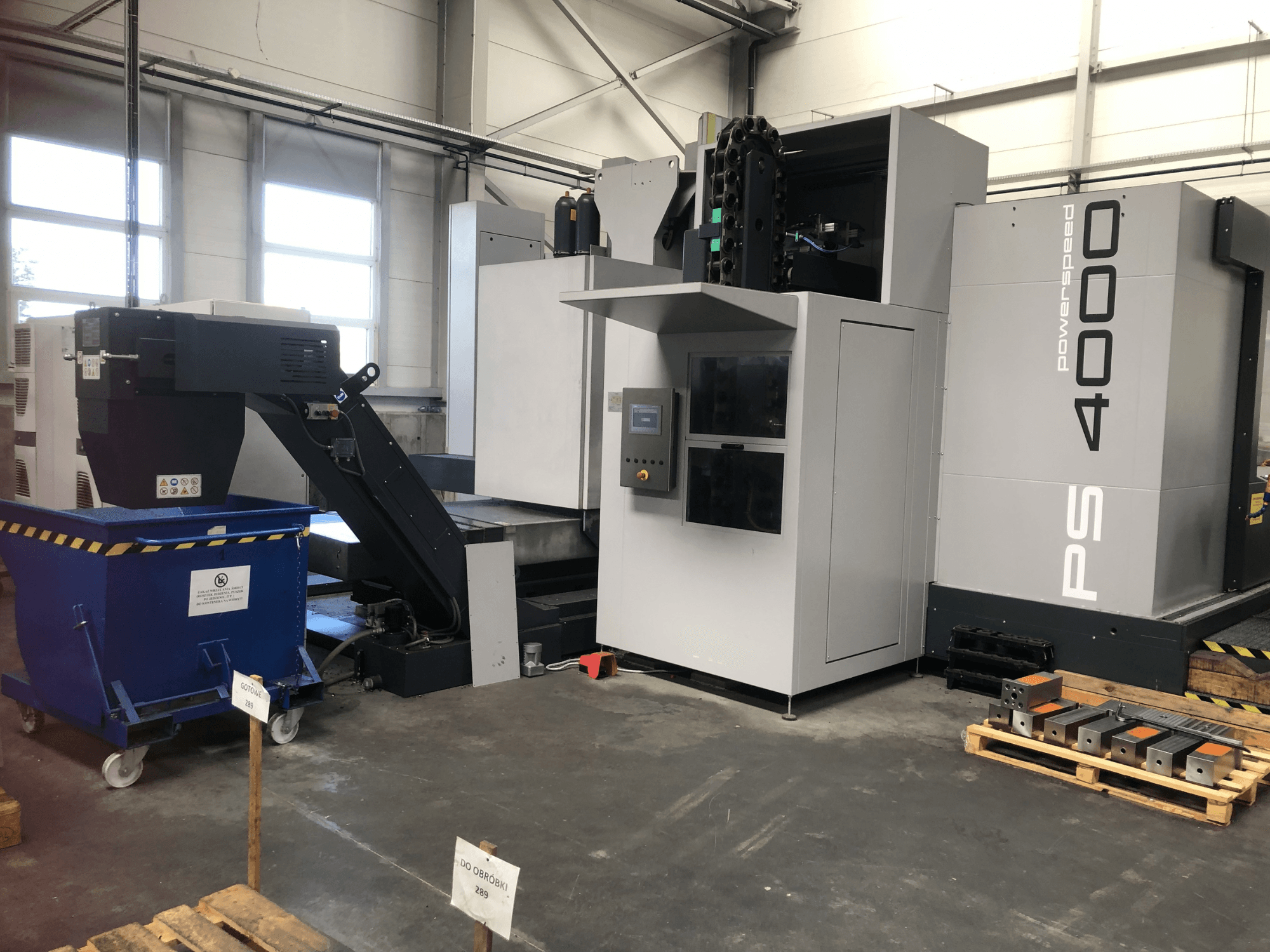 Centre d'usinage horizontal SHW PowerSpeed 4000 dans un environnement d'usine, mettant en avant le panneau de commande, le convoyeur et les pièces à usiner.