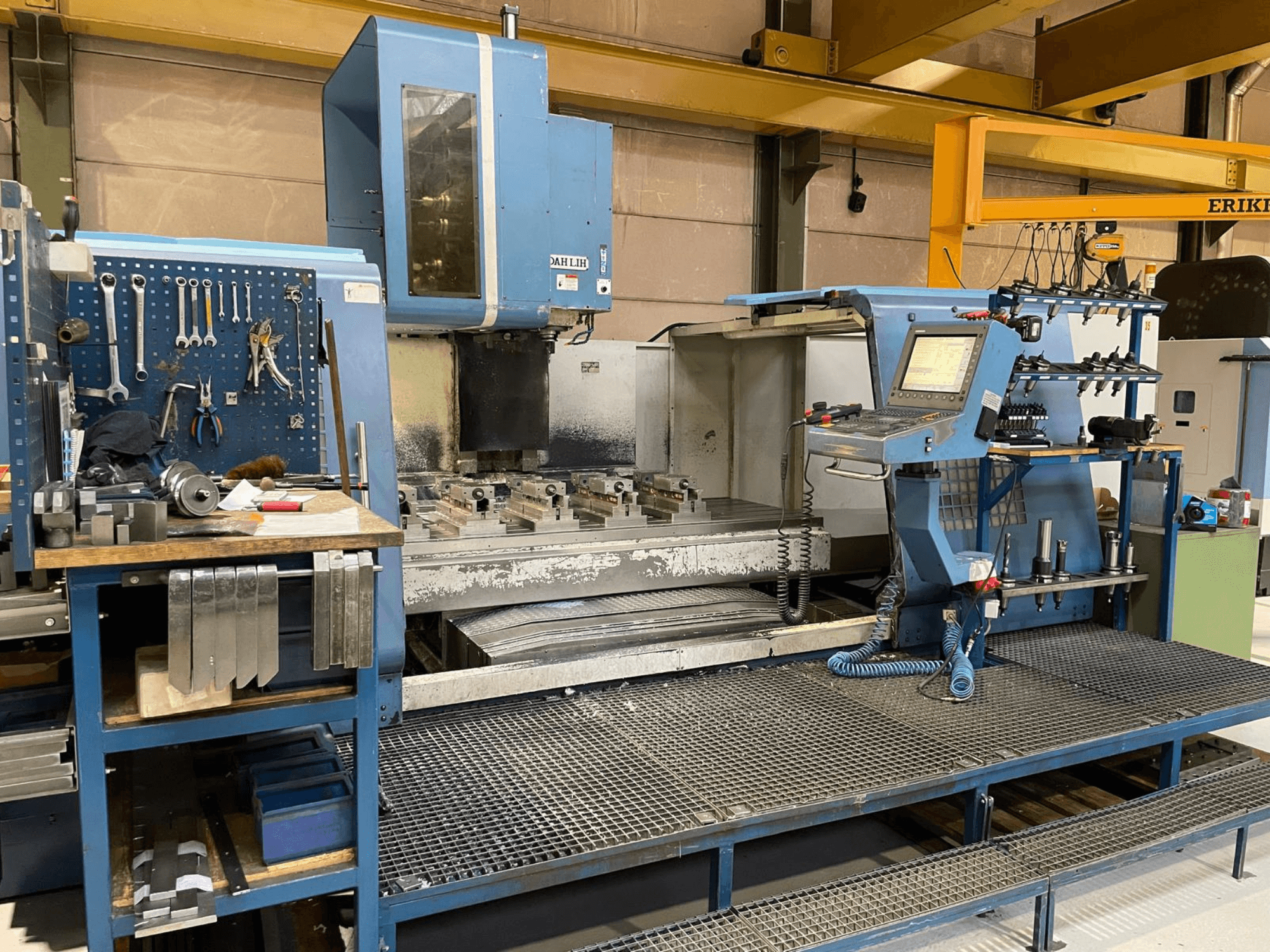 Vue avant du centre d'usinage vertical DAH LIH MCV2600, montrant le panneau de commande, la table de travail et la zone de stockage des outils.