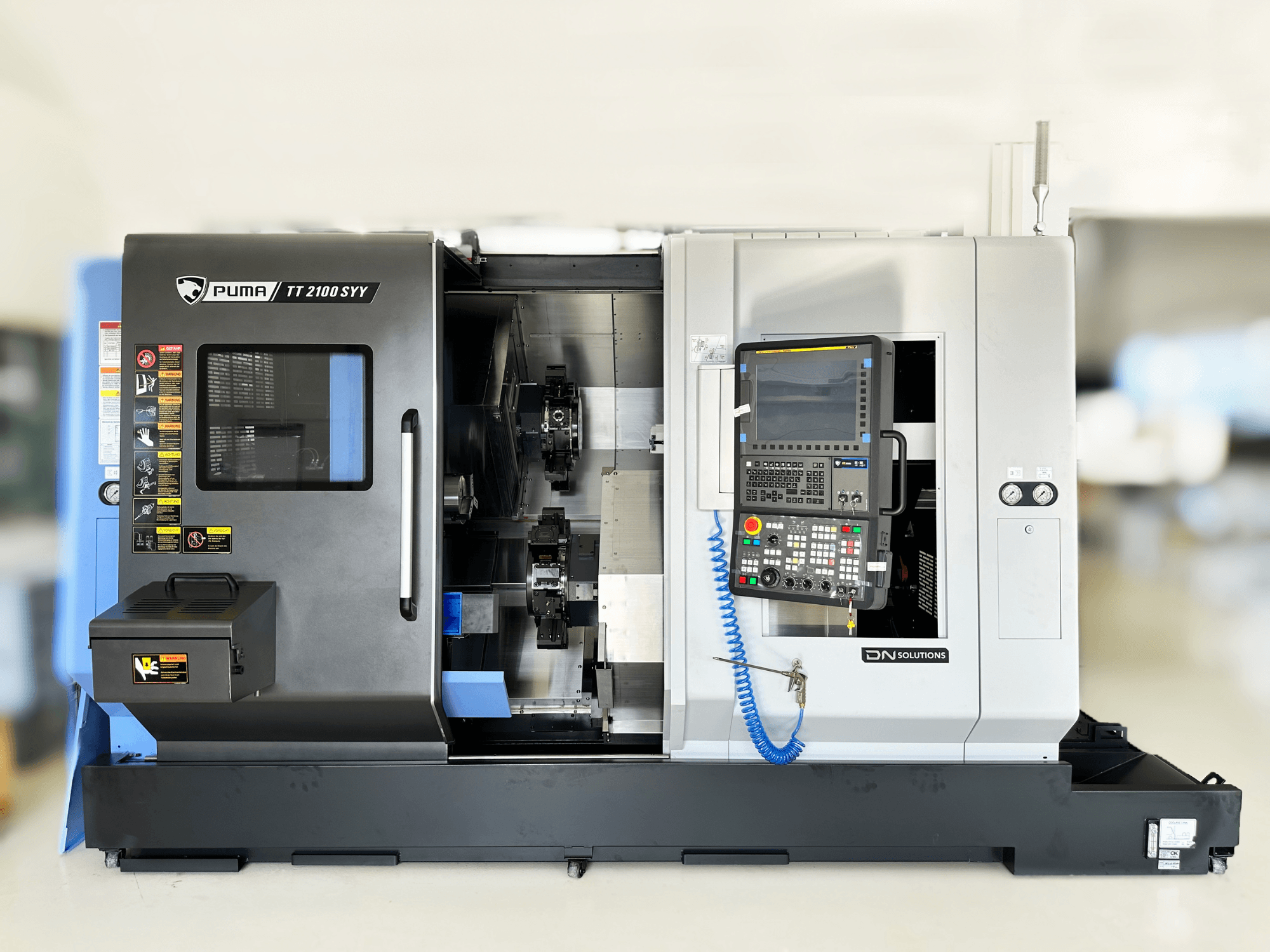 Centre de tournage-fraisage DN SOLUTIONS PUMA TT2100SYY vue de face, avec panneau de commande et composants intérieurs visibles.