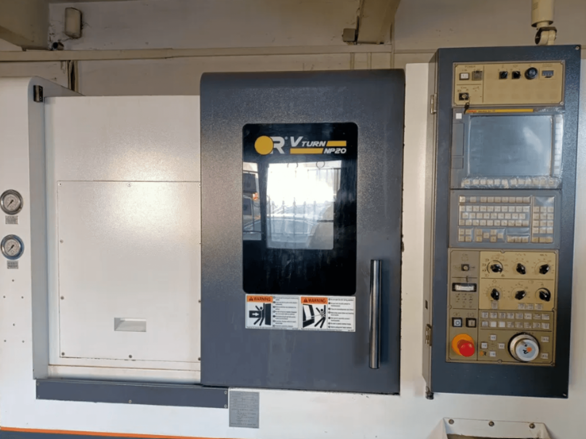 Vue avant de la machine CNC OR VTURN NP20, avec le panneau de commande avec les boutons, l'écran et les jauges sur le côté.