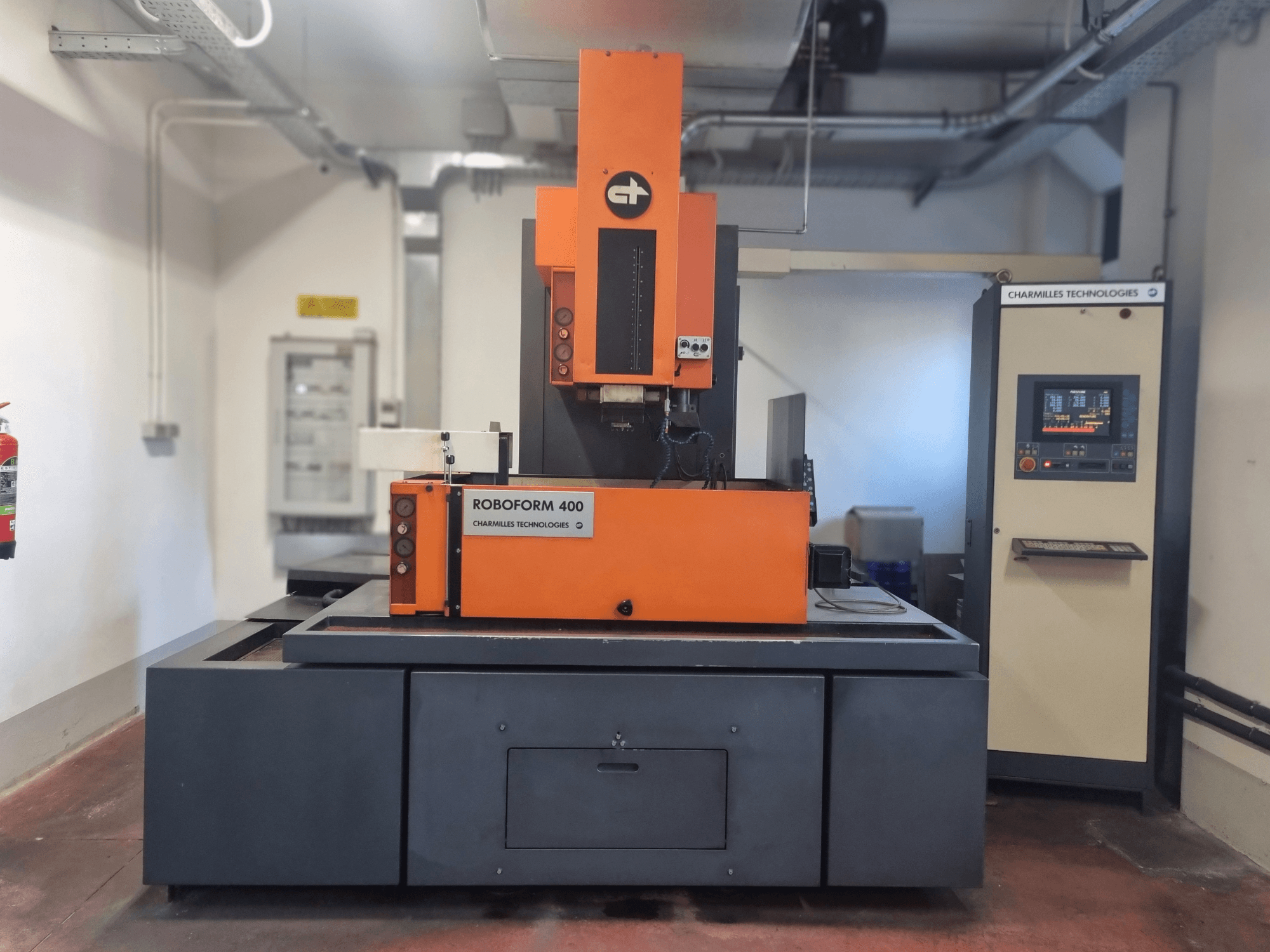 Machine Roboforn 400 de Charmilles Technologies, vue de face, au design orange et gris, panneau de commande numérique visible.