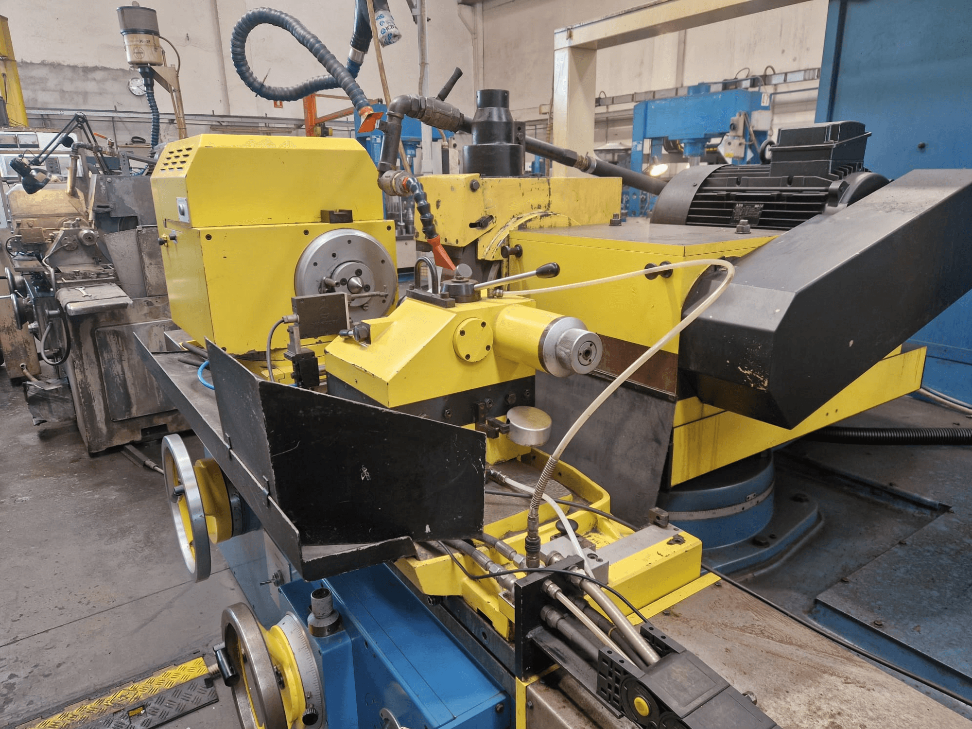 Machine industrielle jaune avec une partie noire, comportant un cadran et des tuyaux, vue de face avec un léger angle.