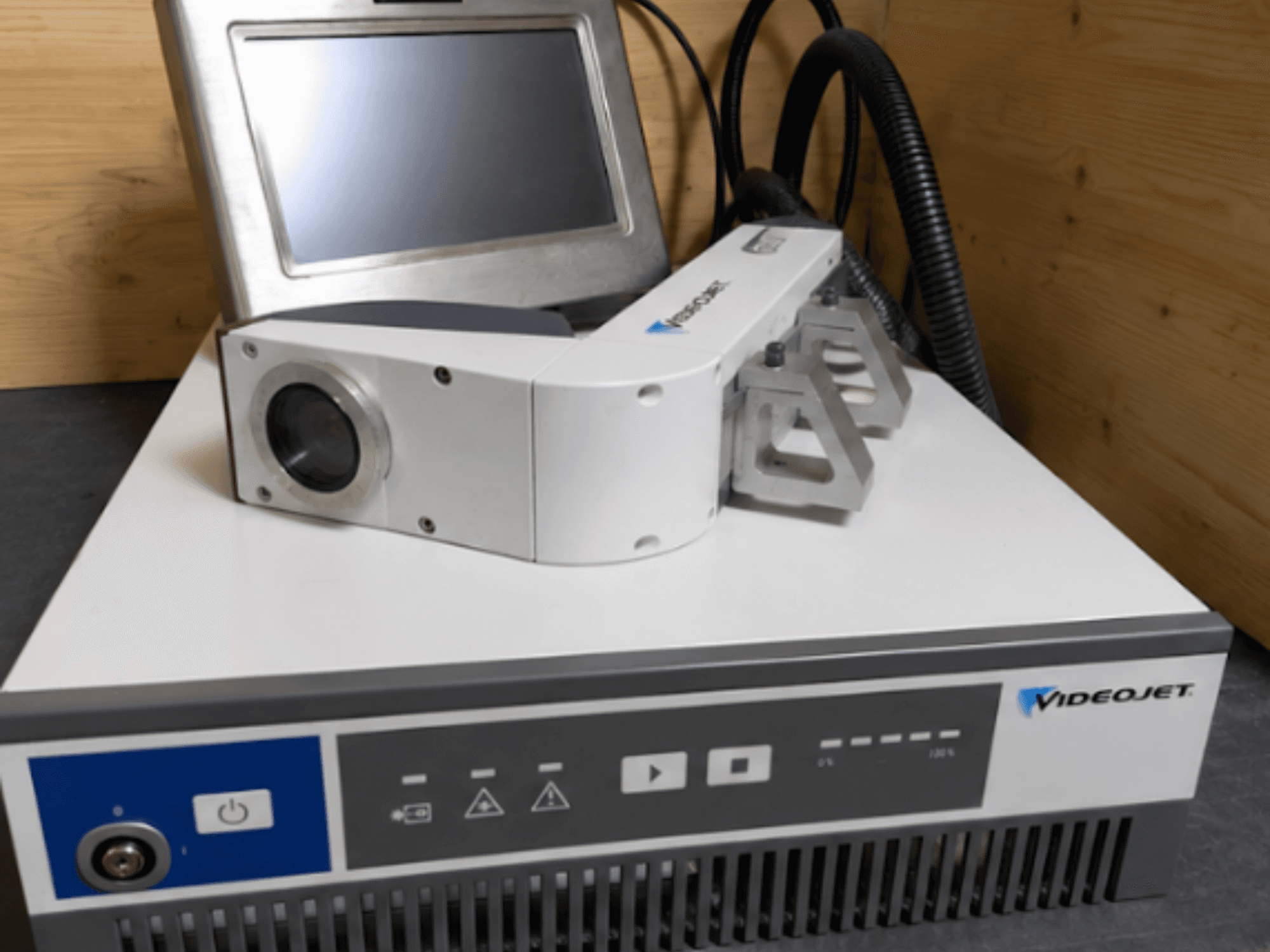 Machine de gravure laser Videojet 7230, vue de face, montrant le panneau de commande et la tête laser avec l'objectif et la fixation.