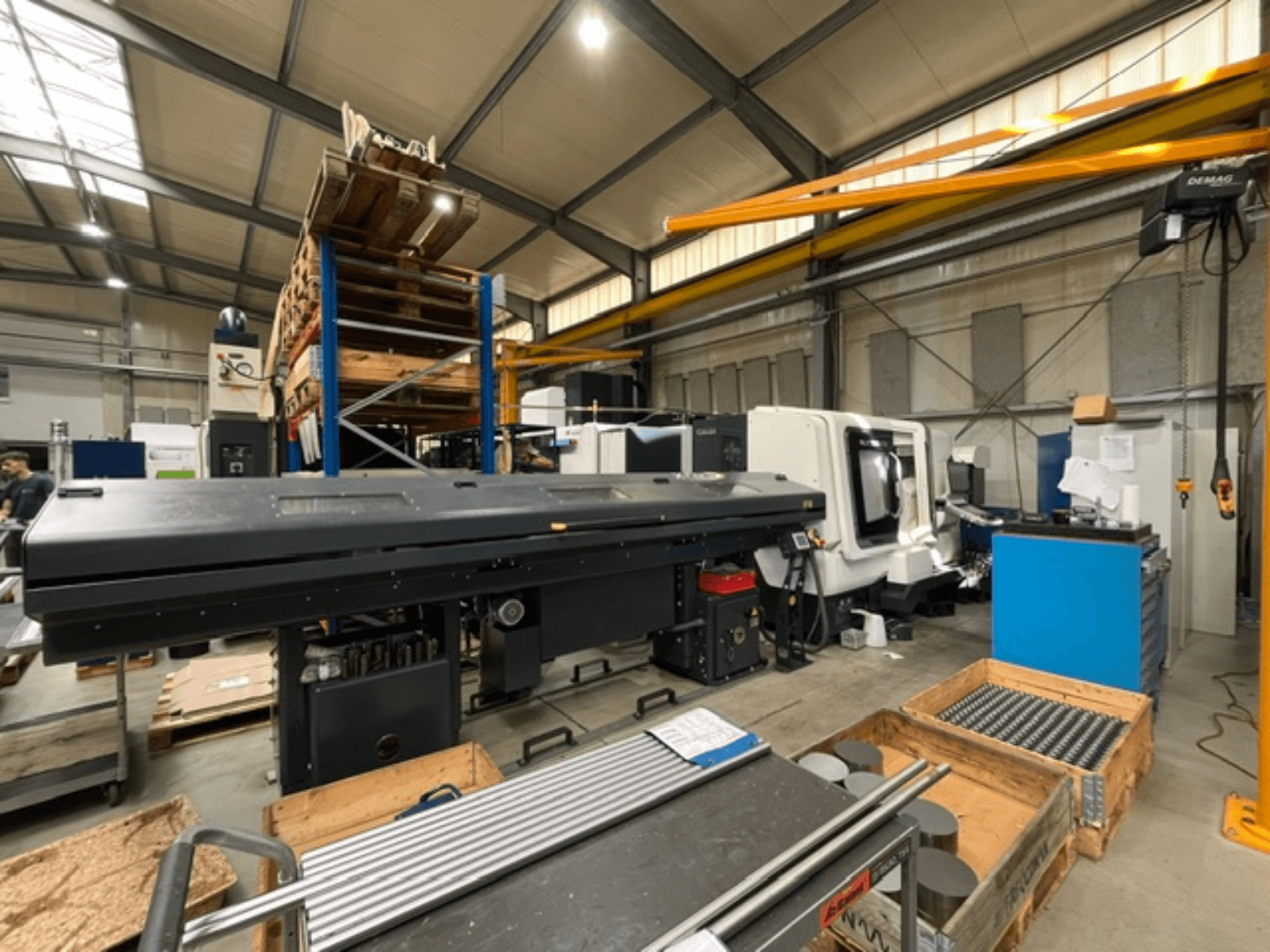 Tour horizontal DMG MORI MORI NLX 2500/700 SY dans un environnement d'usine, vu de profil, avec les outils et les palettes visibles.