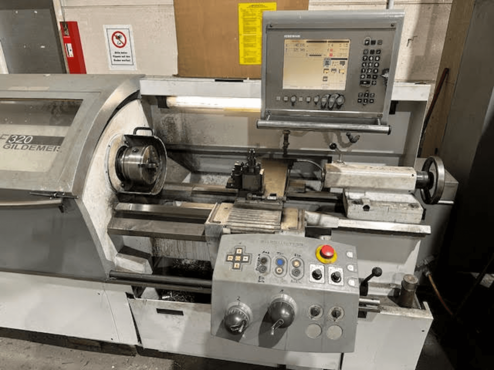 Tour horizontal HERMLE NEF 320, vue de face montrant le panneau de commande, la zone d'outillage et la mise en place de la pièce métallique.